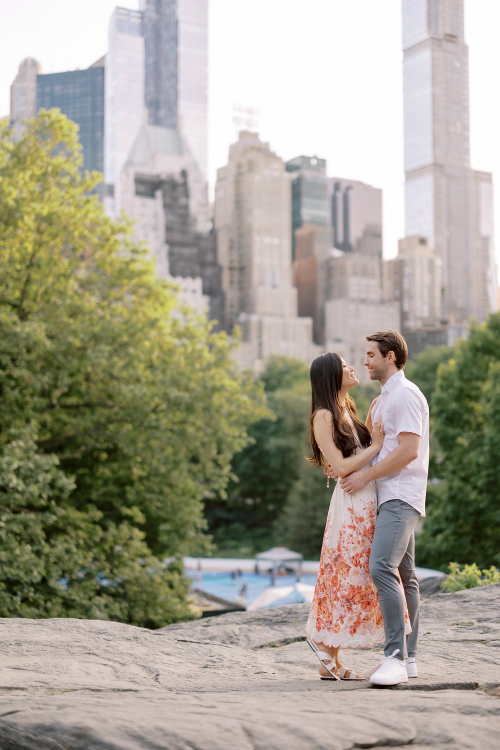 engaged couple stands on rocks during spring engagement portraits in Central Park