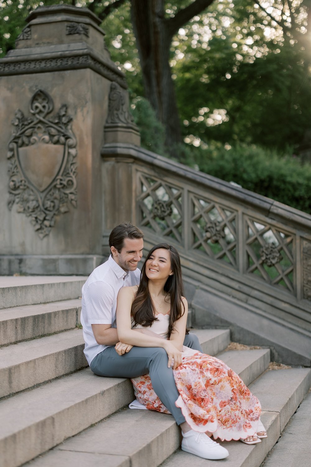 engaged couple sits on steps during spring engagement portraits in Central Park