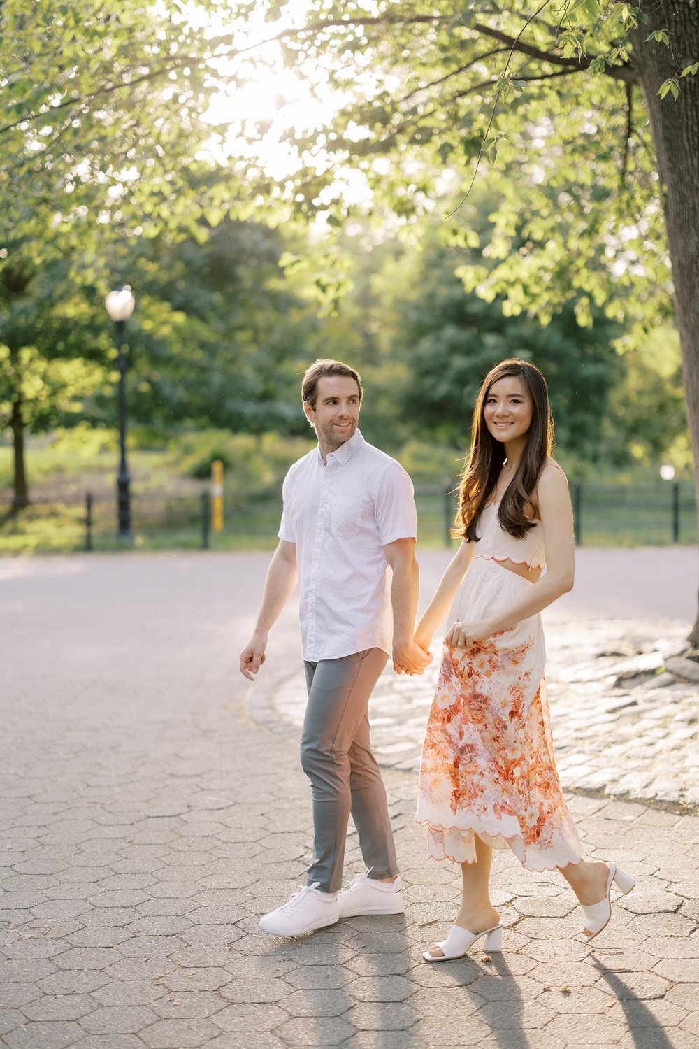 engaged couple walks through Central Park at sunset