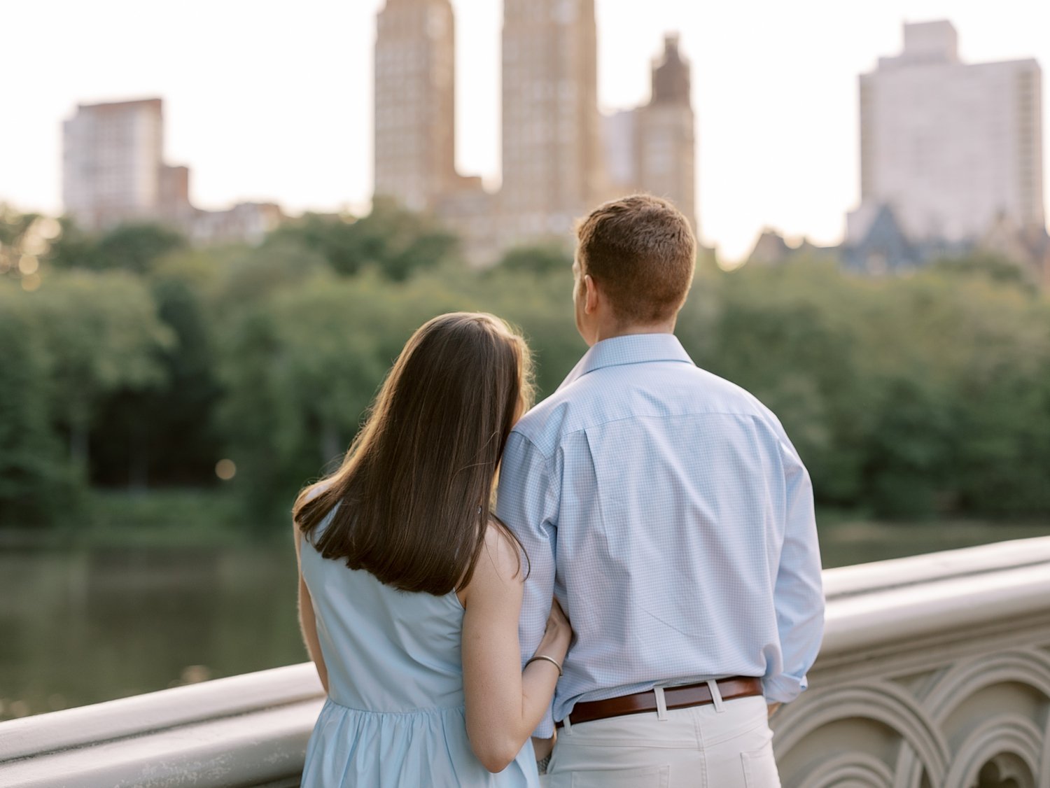 woman leans head on man's shoulder looking at NYC skyline from Central Park