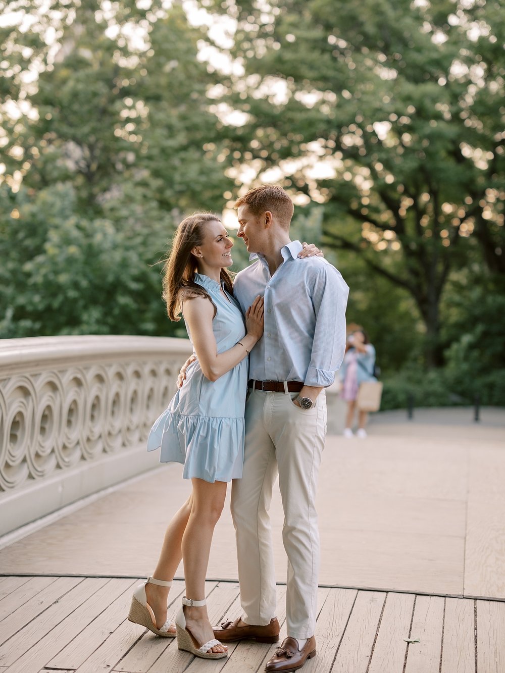engaged couple hugs on pathway in Central Park