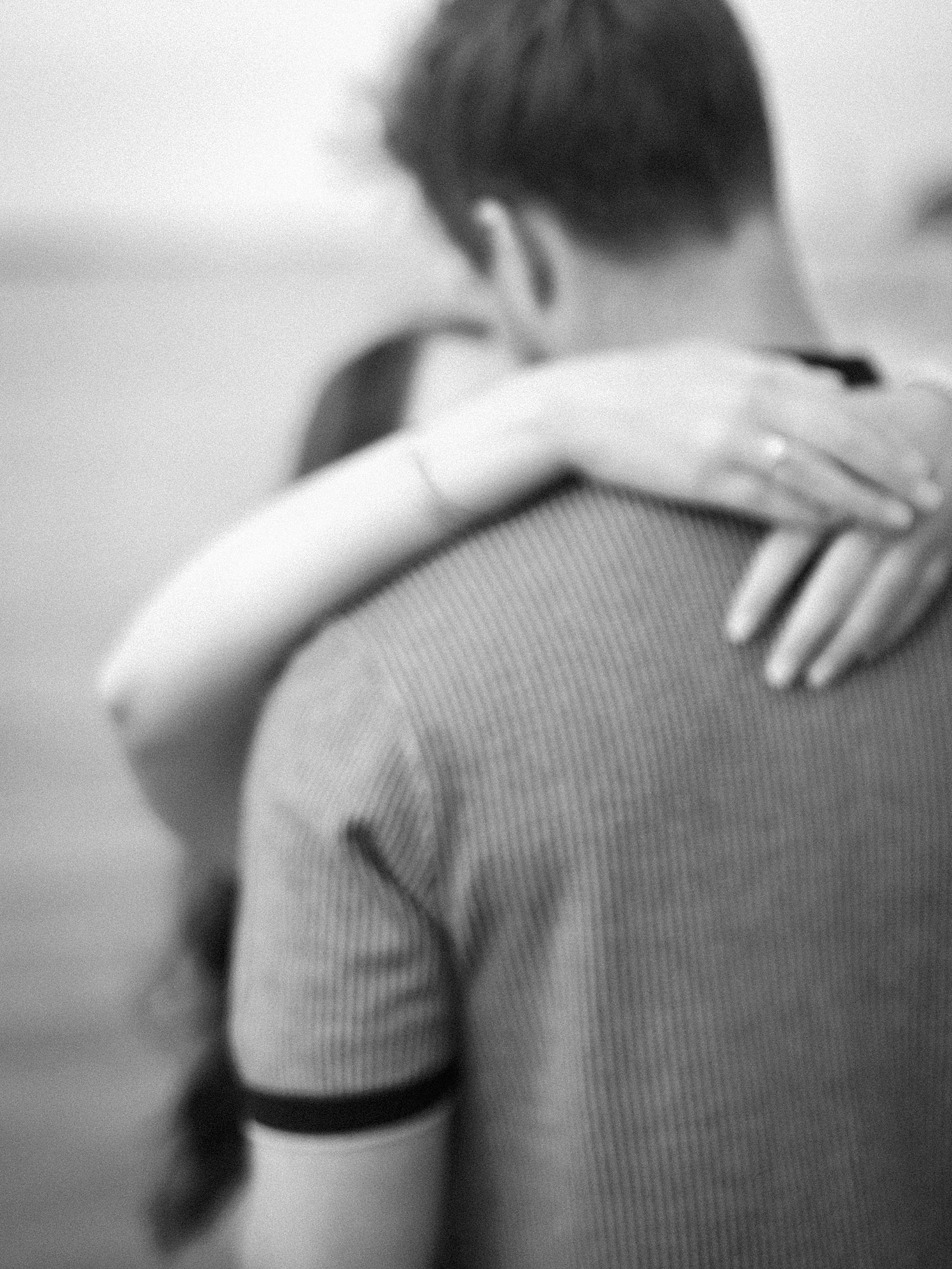 woman rests hands behind man's neck showing off ring