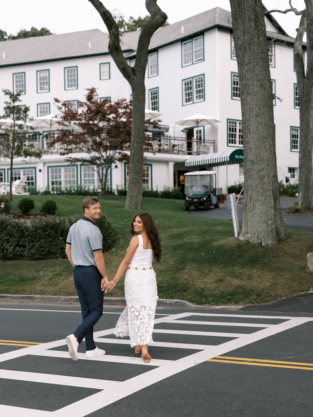 woman in white dress looks over shoulder walking with man through New York