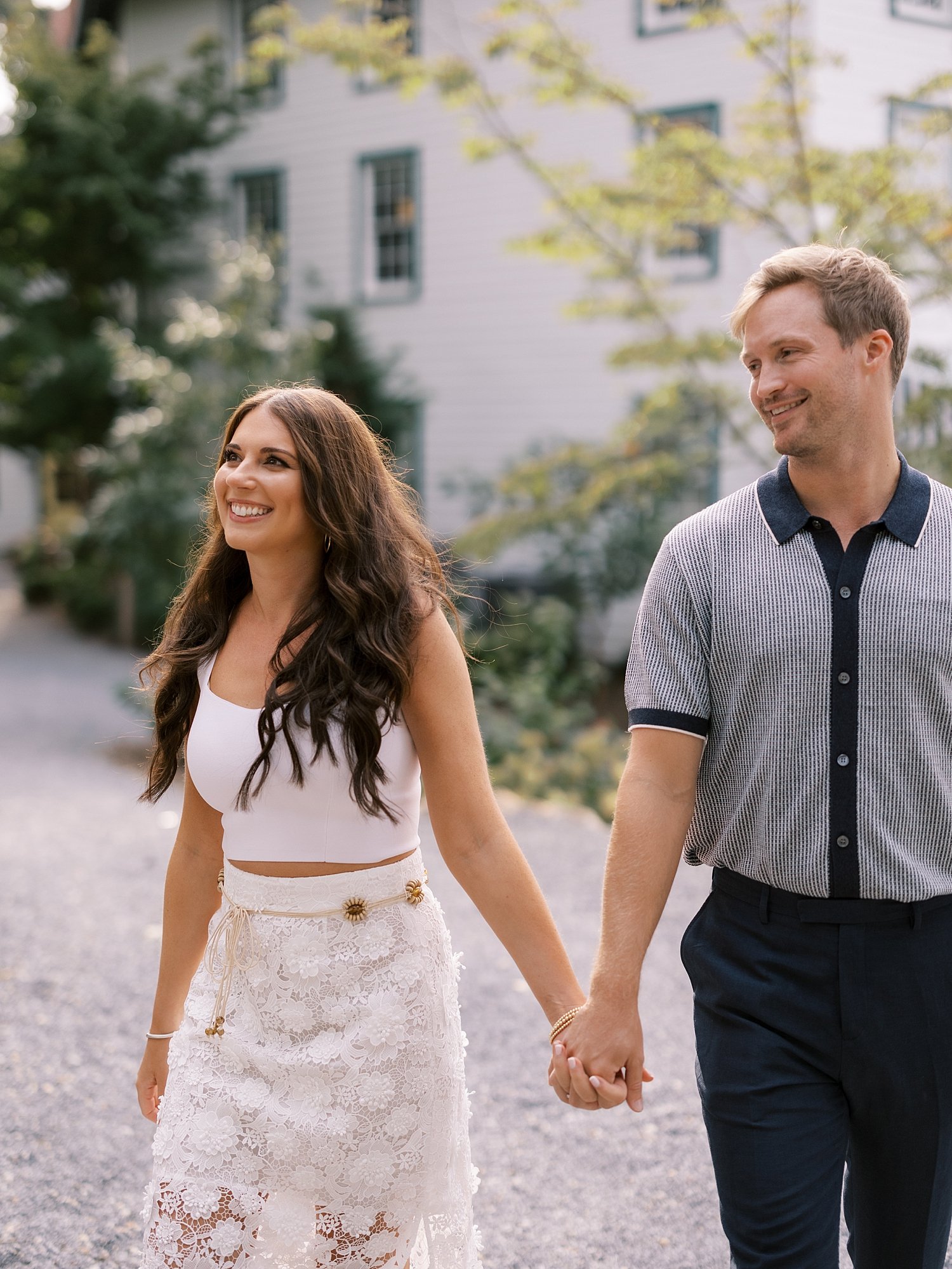 man and woman hold hands walking outside Shelter Island hotel