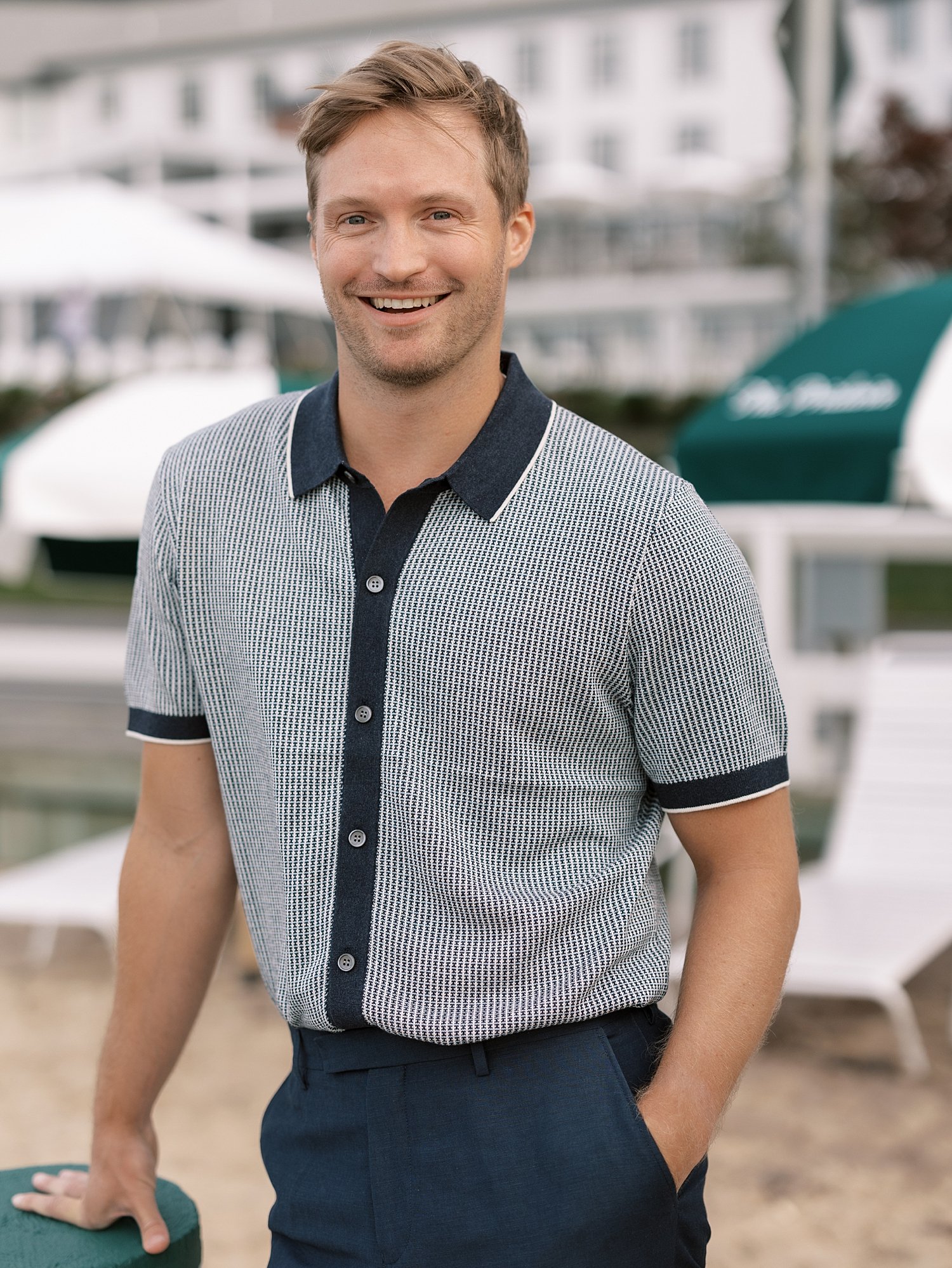 man in blue polo smiles on beach of Shelter Island hotel