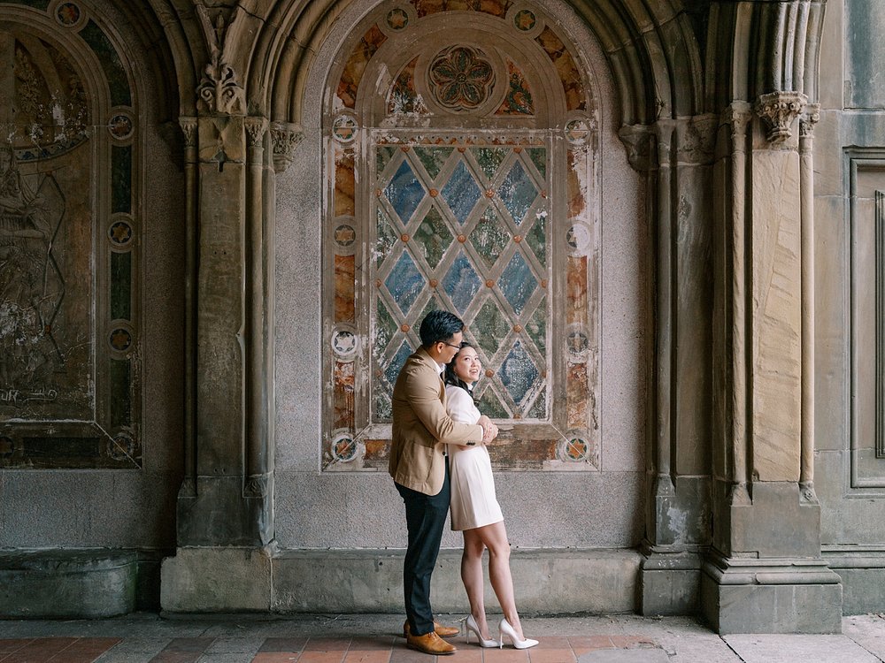 couple hugs in front of mural under Bethesda Terrace in Central Park