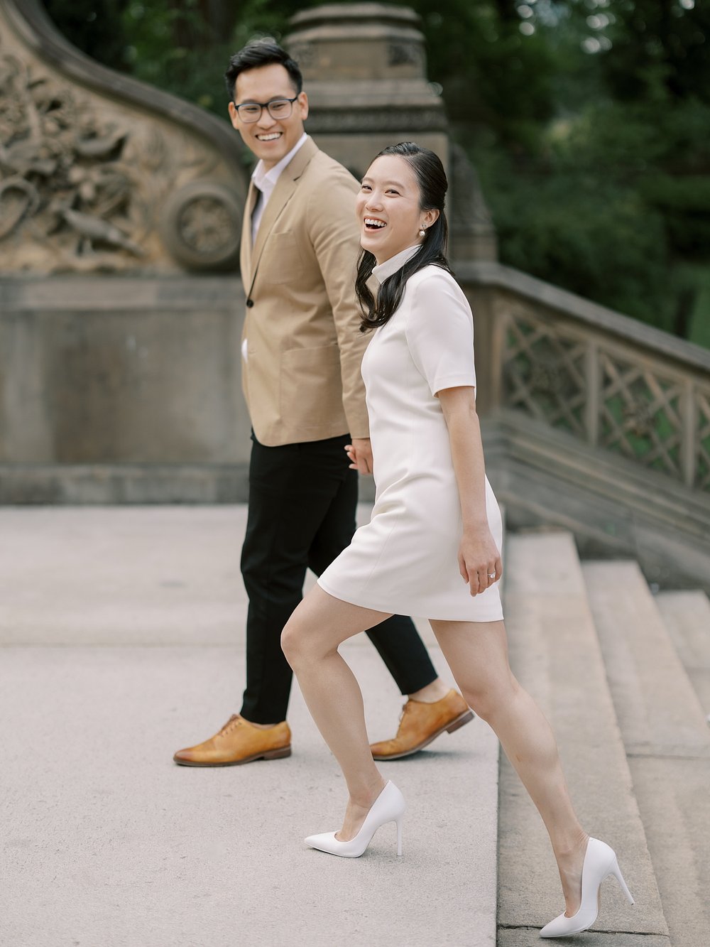 woman laughs walking up steps of Bethesda Terrace in Central Park with fiance