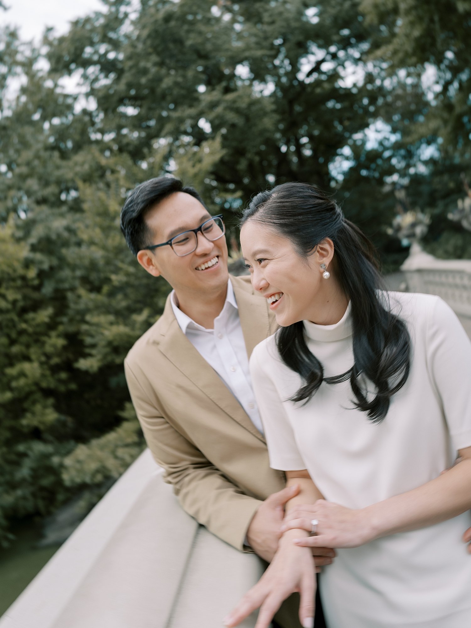 woman laughs leaning into man on railing in Central Park