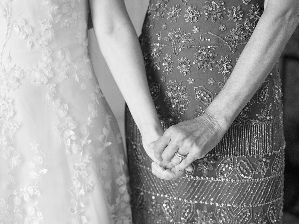 bride and mom hold hands on wedding morning