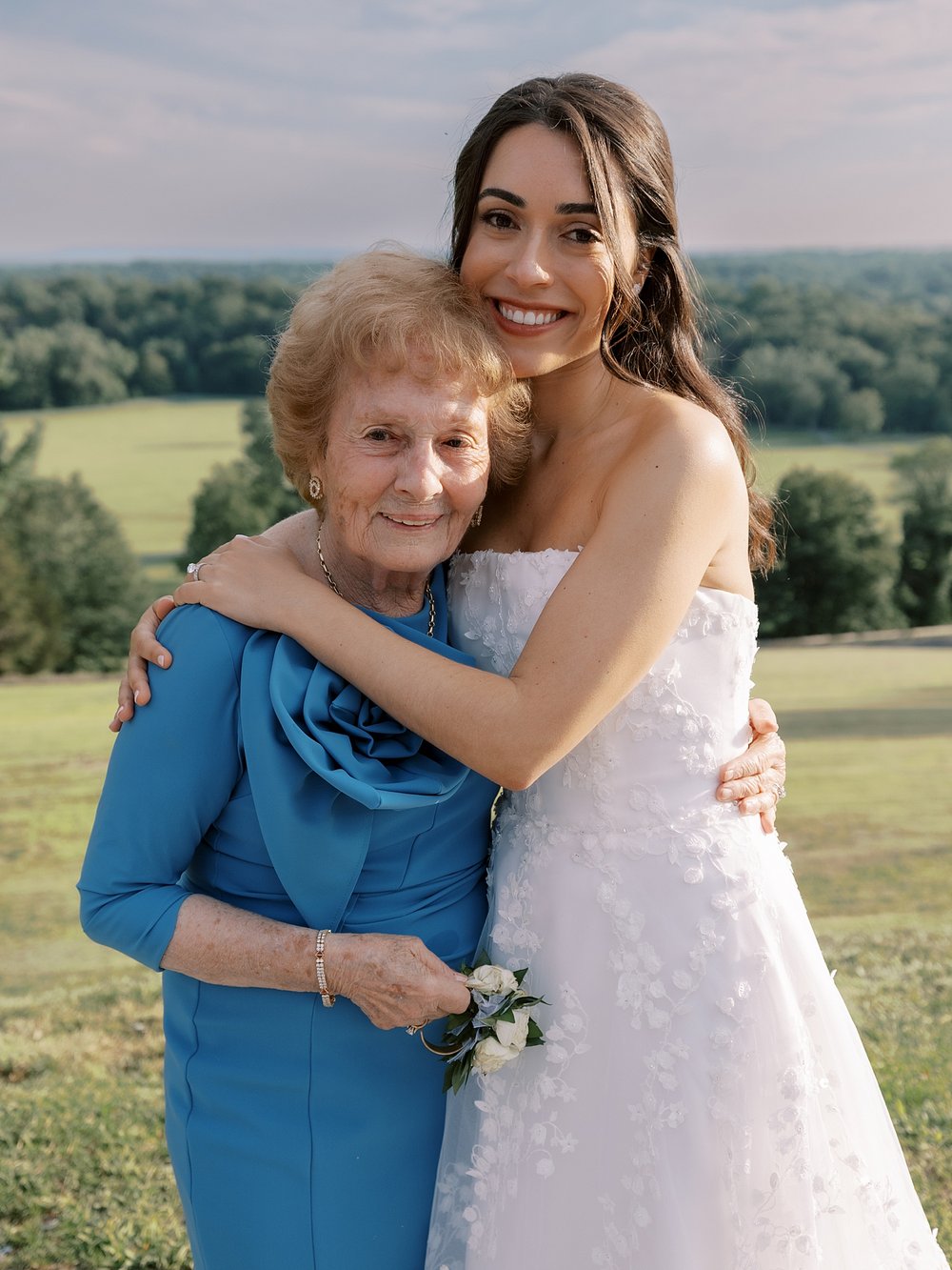 bride hugs grandmother on hill outside the Mansion at Natirar