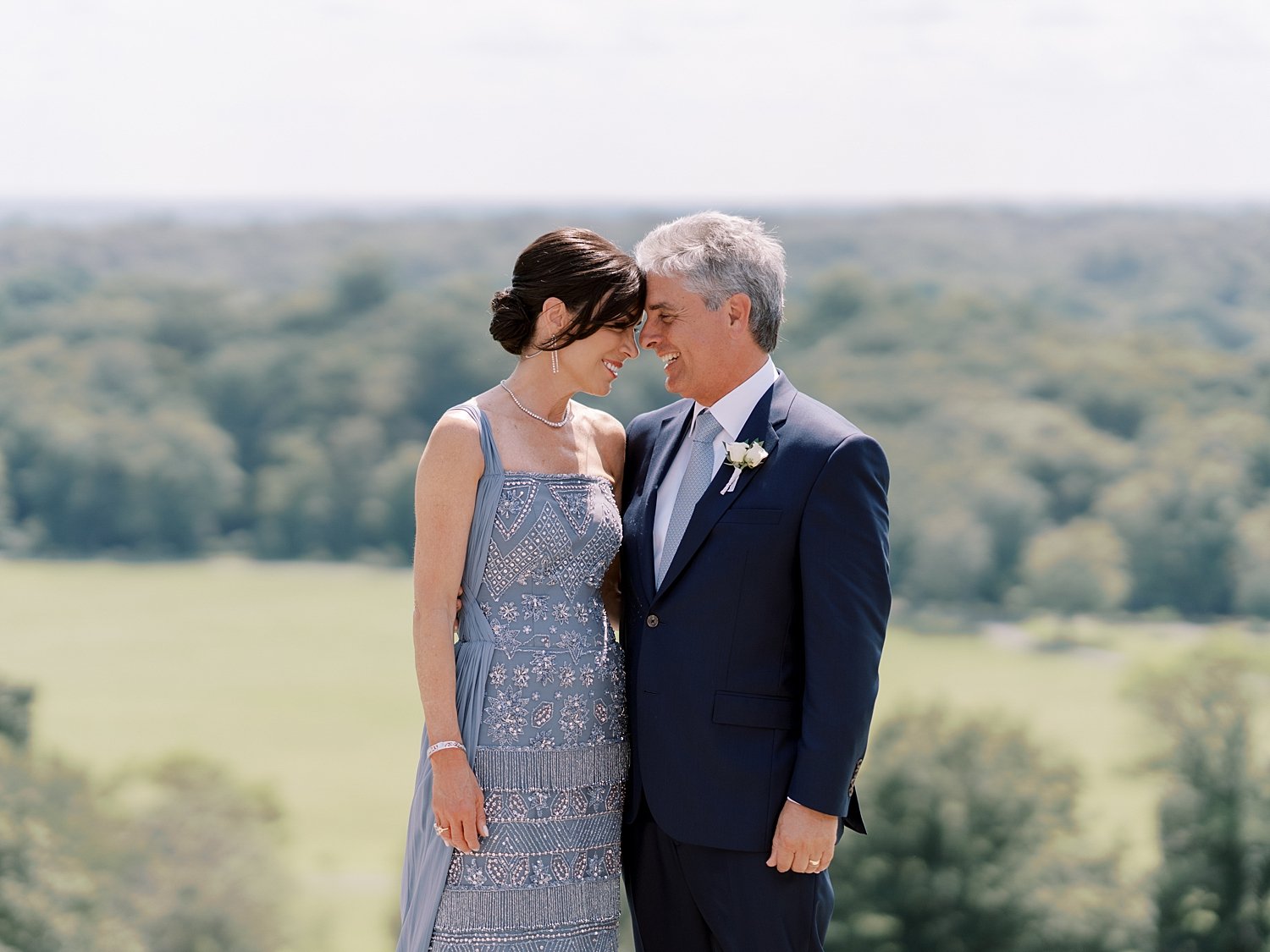 mother and father lean heads together on hill at the Mansion at Natirar