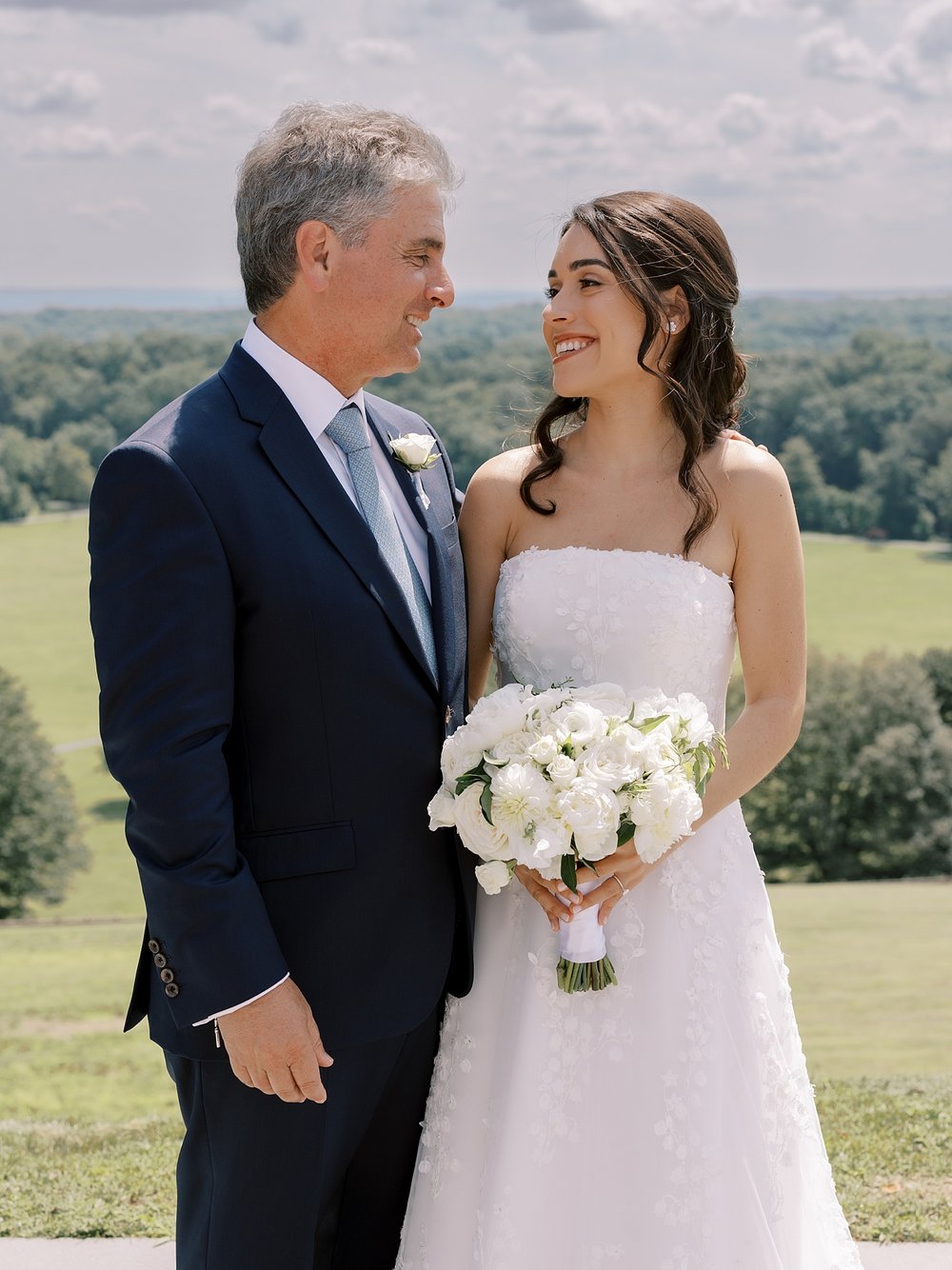 bride smiles at dad standing on hill outside the Mansion at Natirar