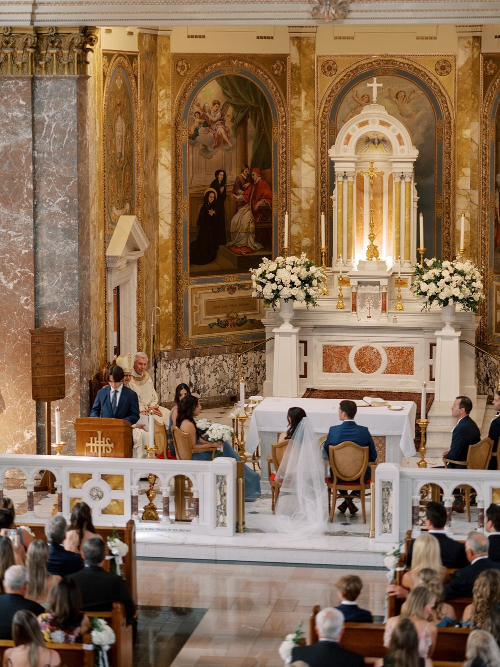 bride and groom sit during Catholic wedding inside the chapel at the Villa Walsh Academy