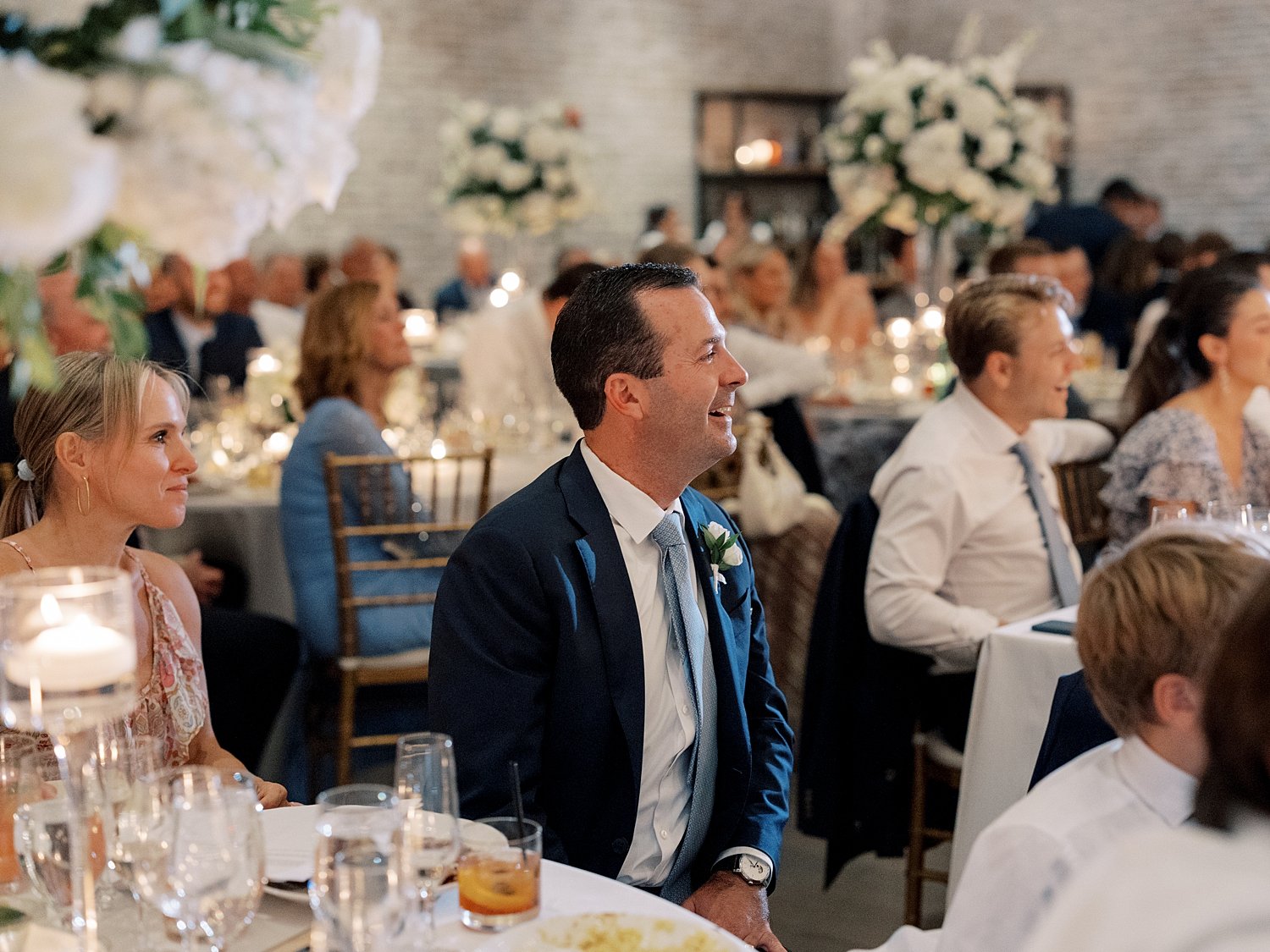 man listens to toast twisting in chair during reception 