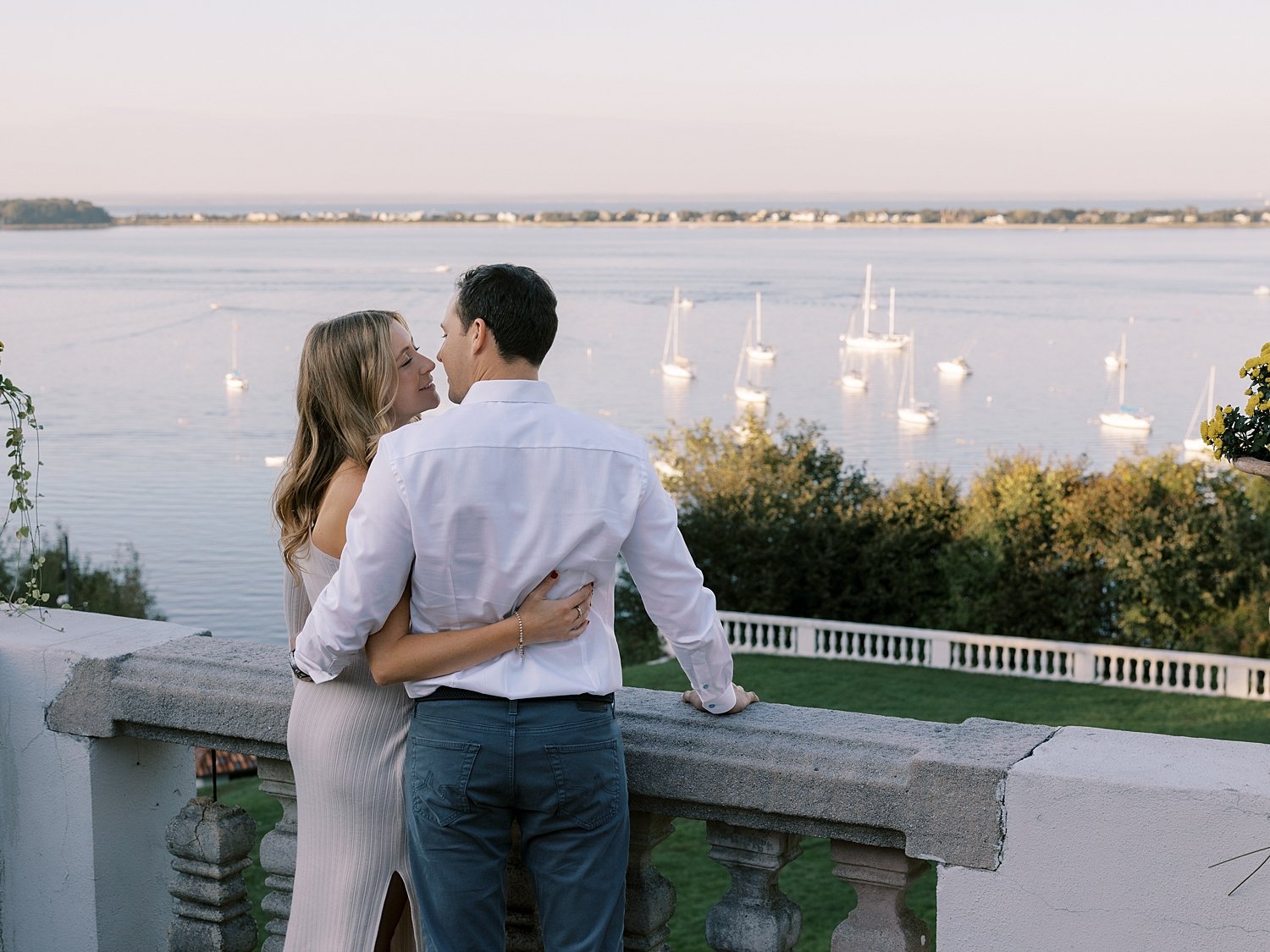 bride and groom lean to kiss overlooking water at the Vanderbilt Museum