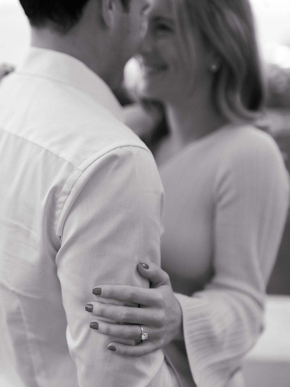 woman holds man's arm showing off her engagement ring