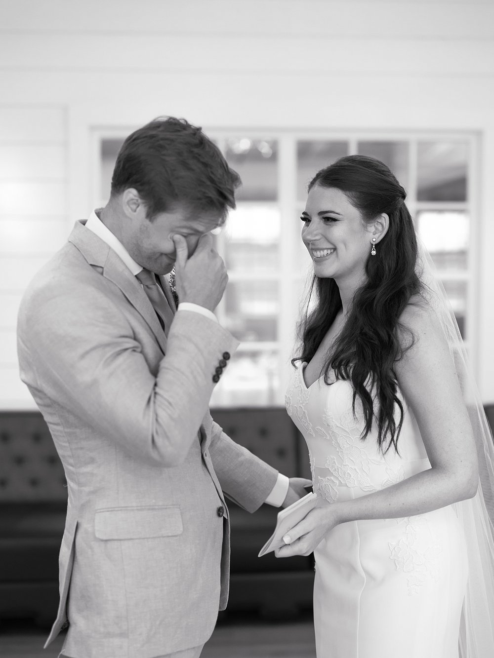 bride grins at groom while he cries during first look