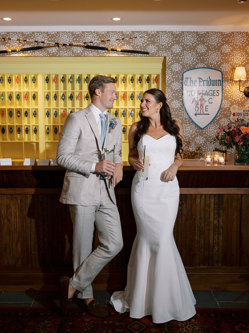 bride and groom pose against front desk of the Pridwin