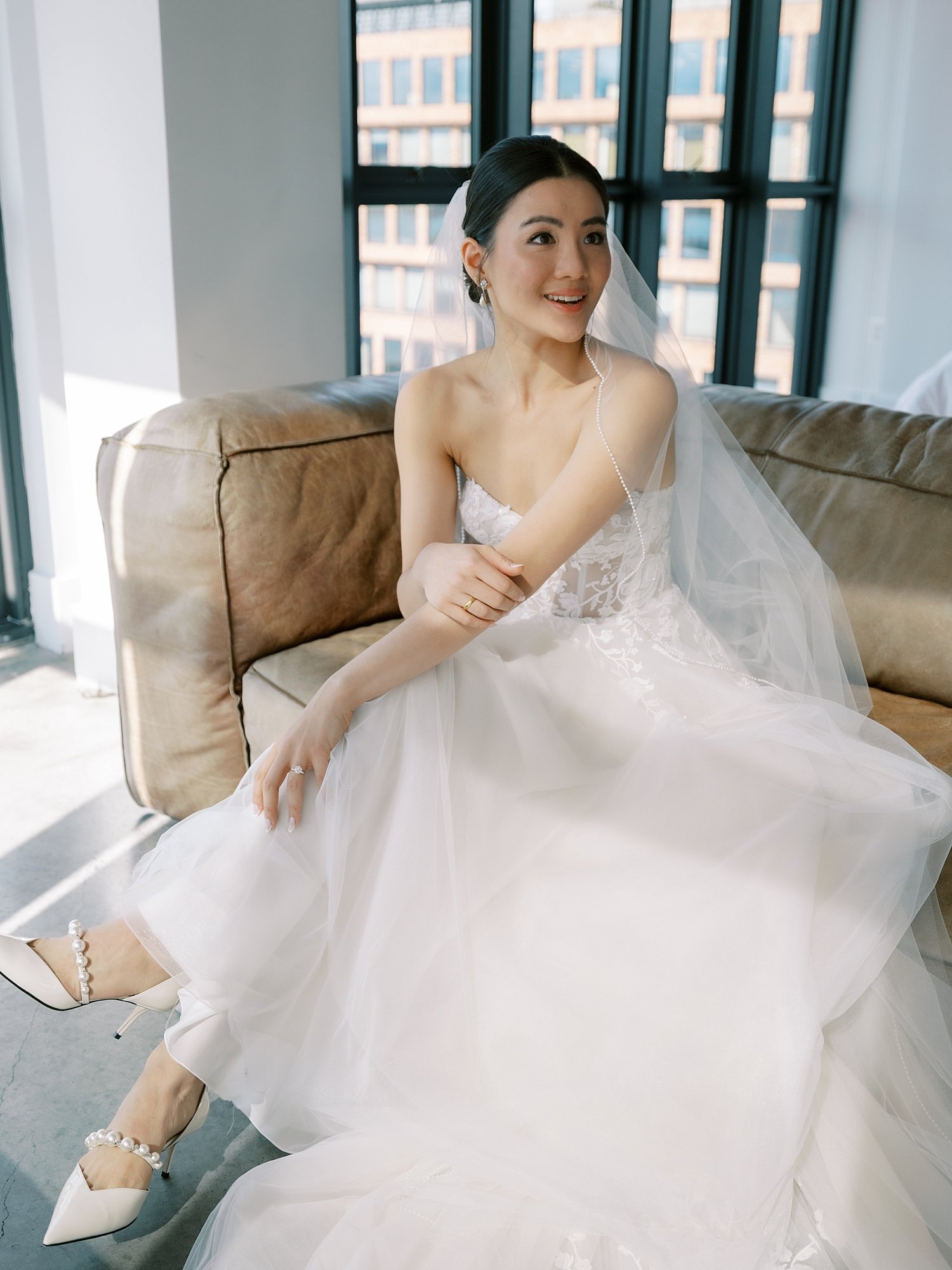 bride sits on couch looking over shoulder at the Wythe Hotel in Brooklyn NY