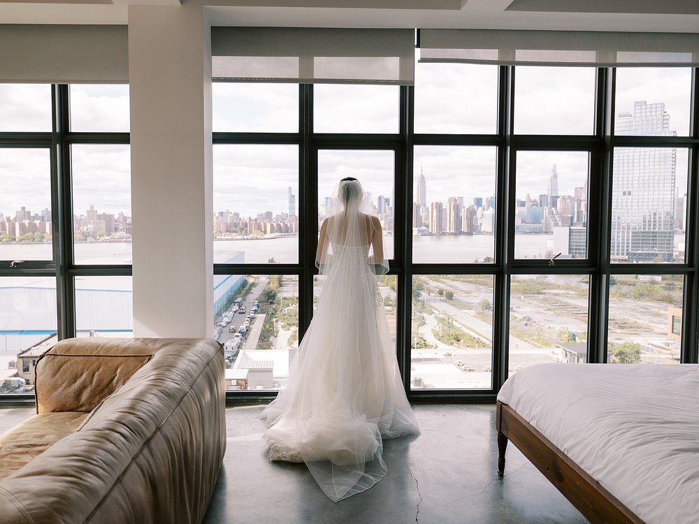 bride looks out hotel window overlooking Brooklyn NYC