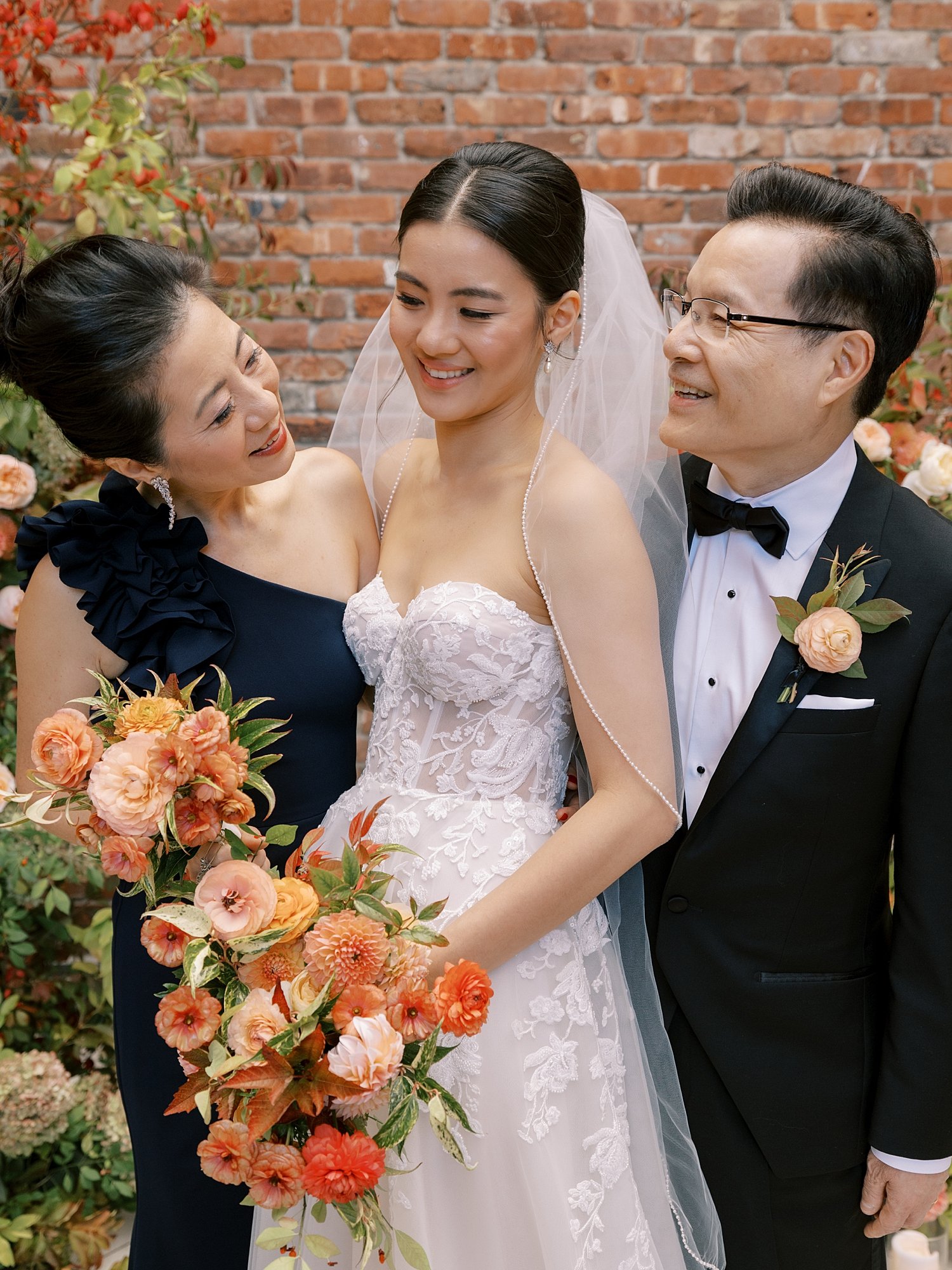 bride and groom pose with family in front of brick wall at the Wythe Hotel