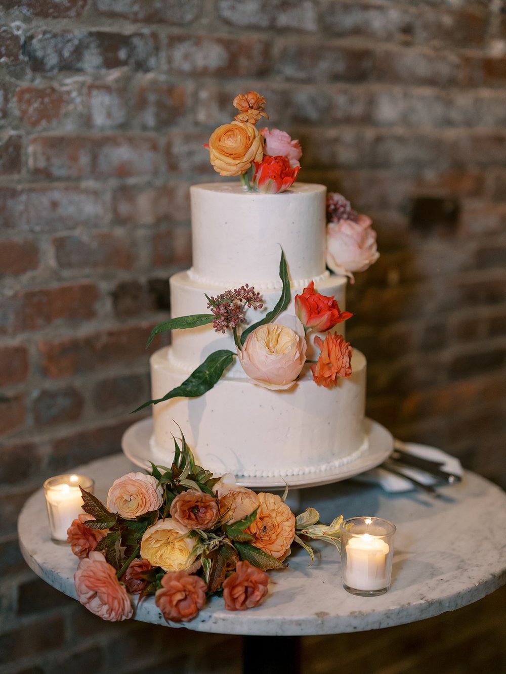 tiered wedding cake with orange and coral flowers