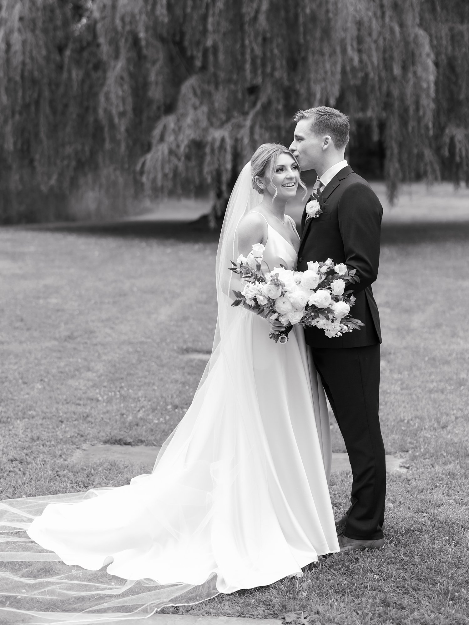 bride and groom hug in front of weeping willow at the Buttermilk Inn &amp; Spa