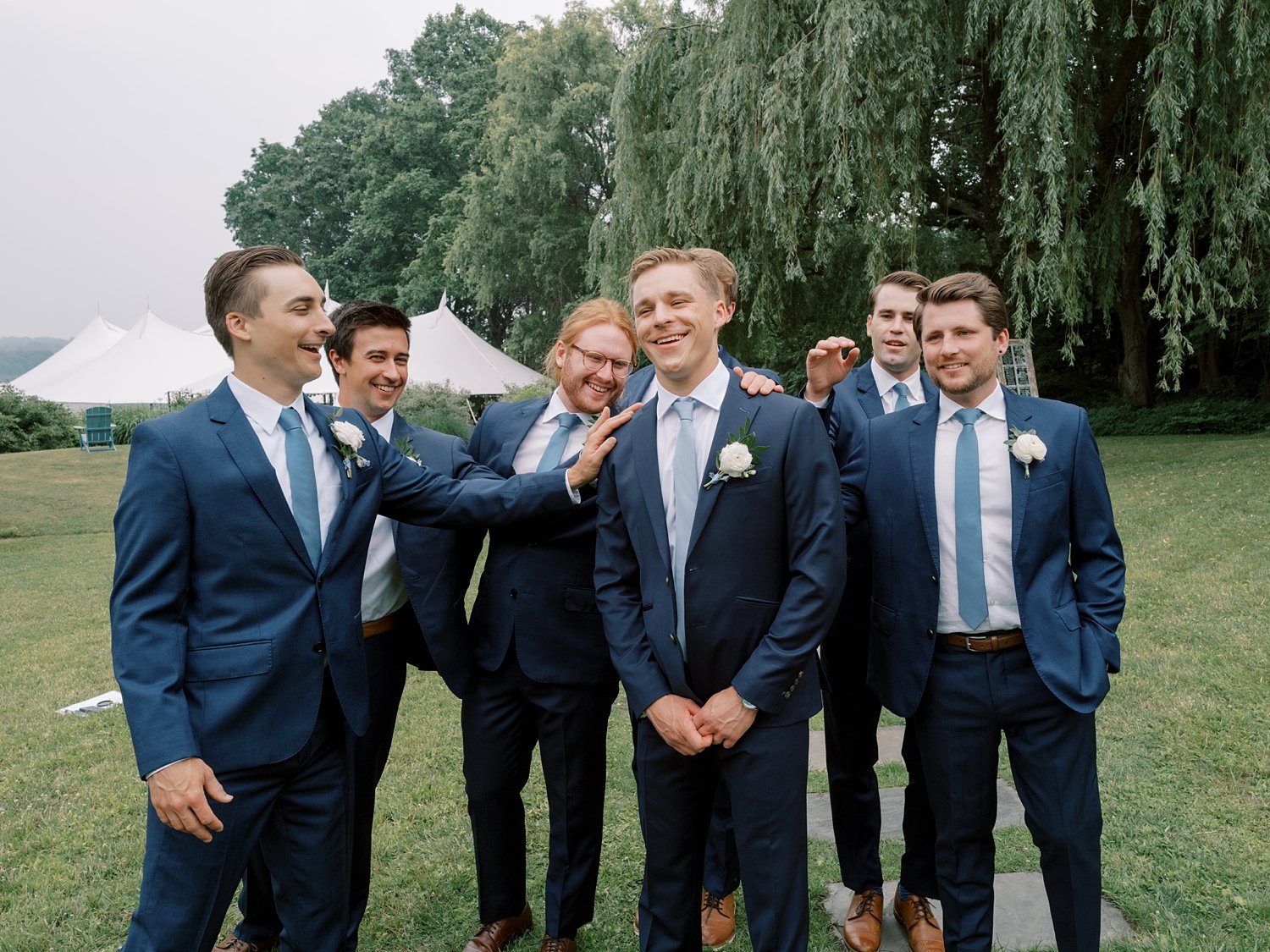 groom laughs with groomsmen in navy suits 