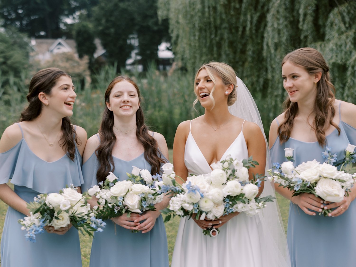 bride laughs with bridesmaids in light blue gowns 