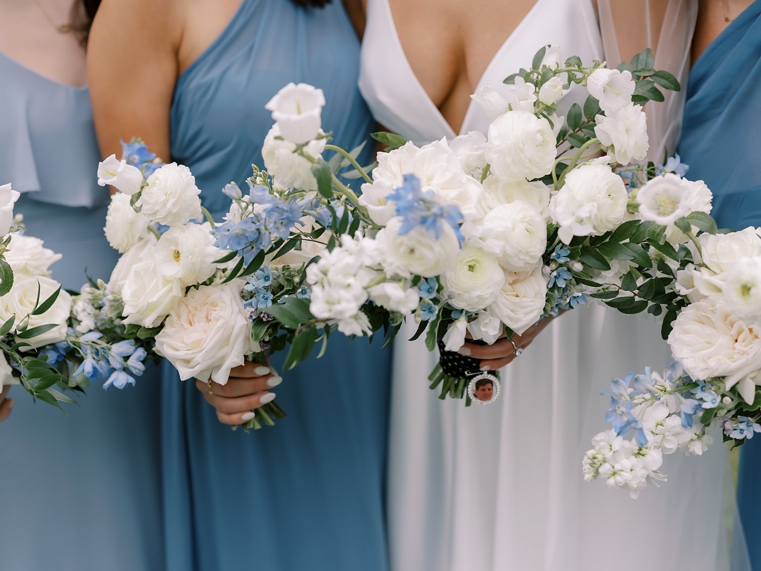 bride stands with bridesmaids in light blue gowns with white and blue flowers 