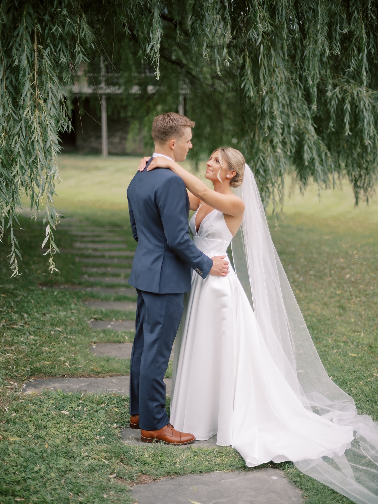 bride and groom hug near weeping willow at the Buttermilk Inn &amp; Spa