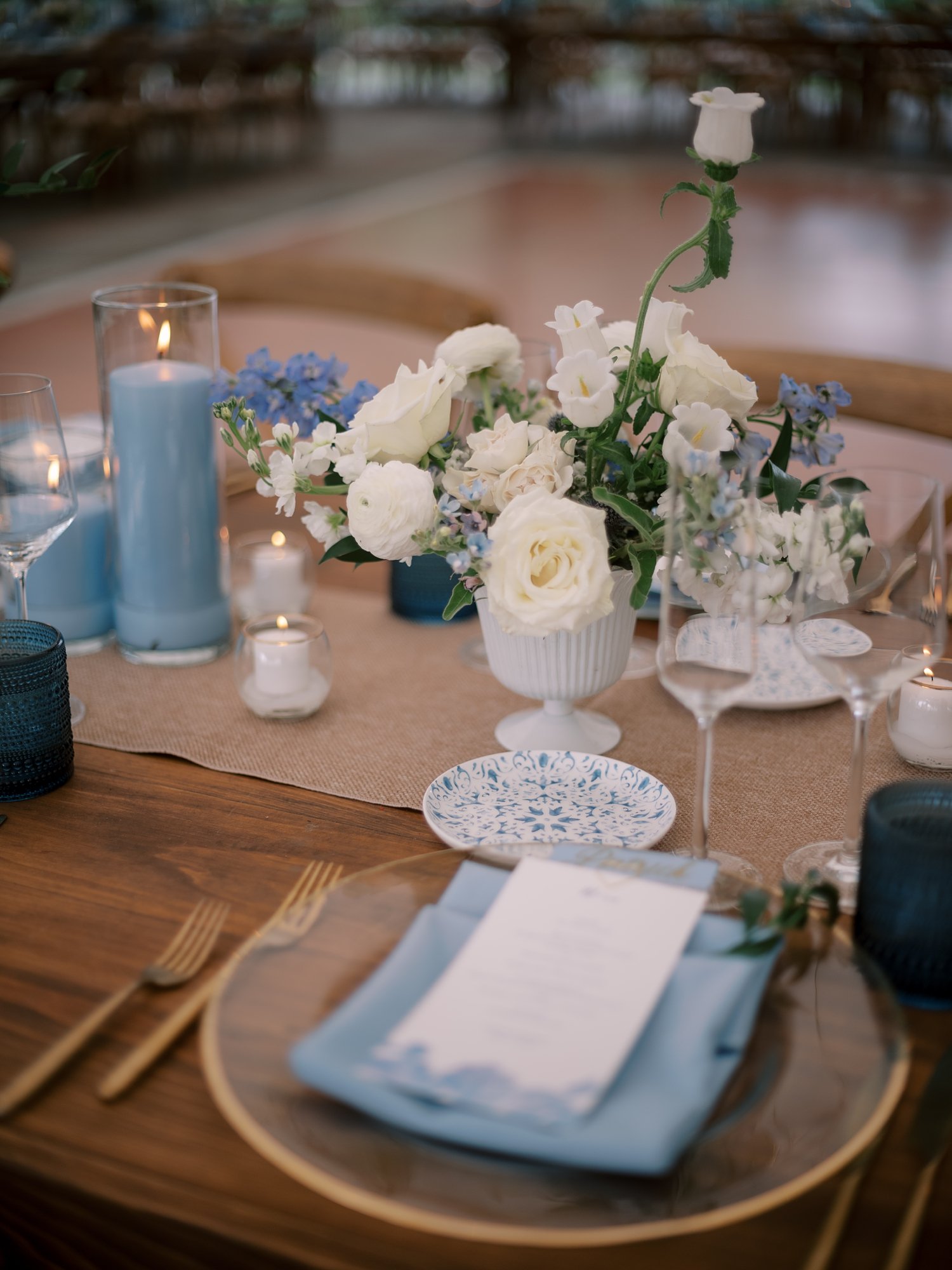 place setting for tented wedding reception with blue napkins and white flowers 