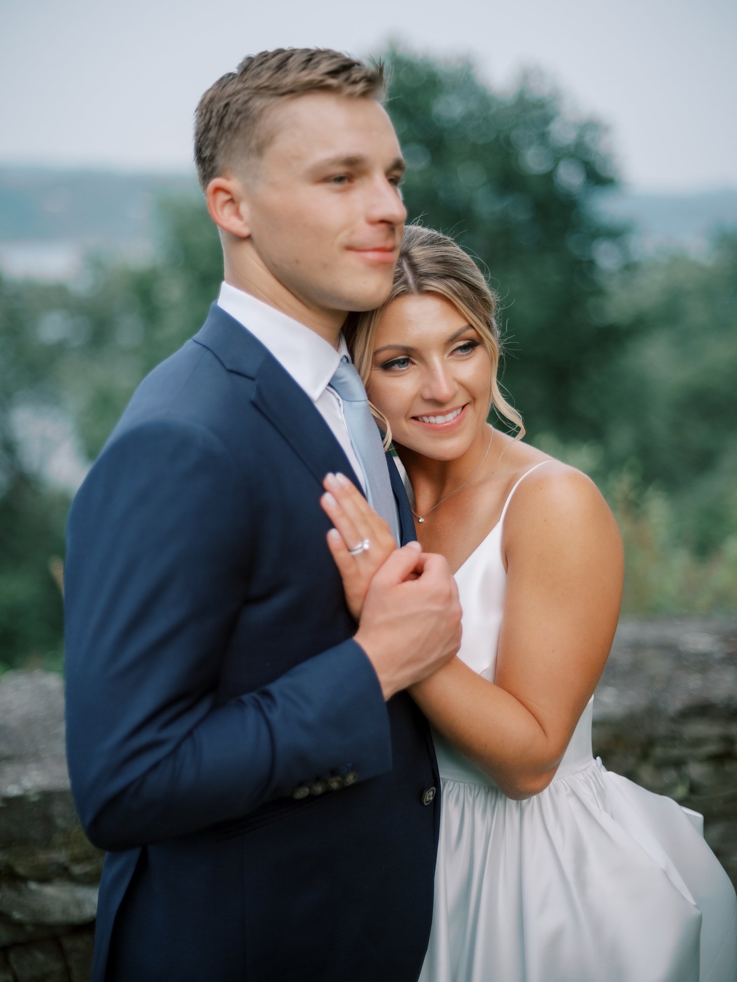 bride leans on groom's chest in navy suit at the Buttermilk Inn &amp; Spa