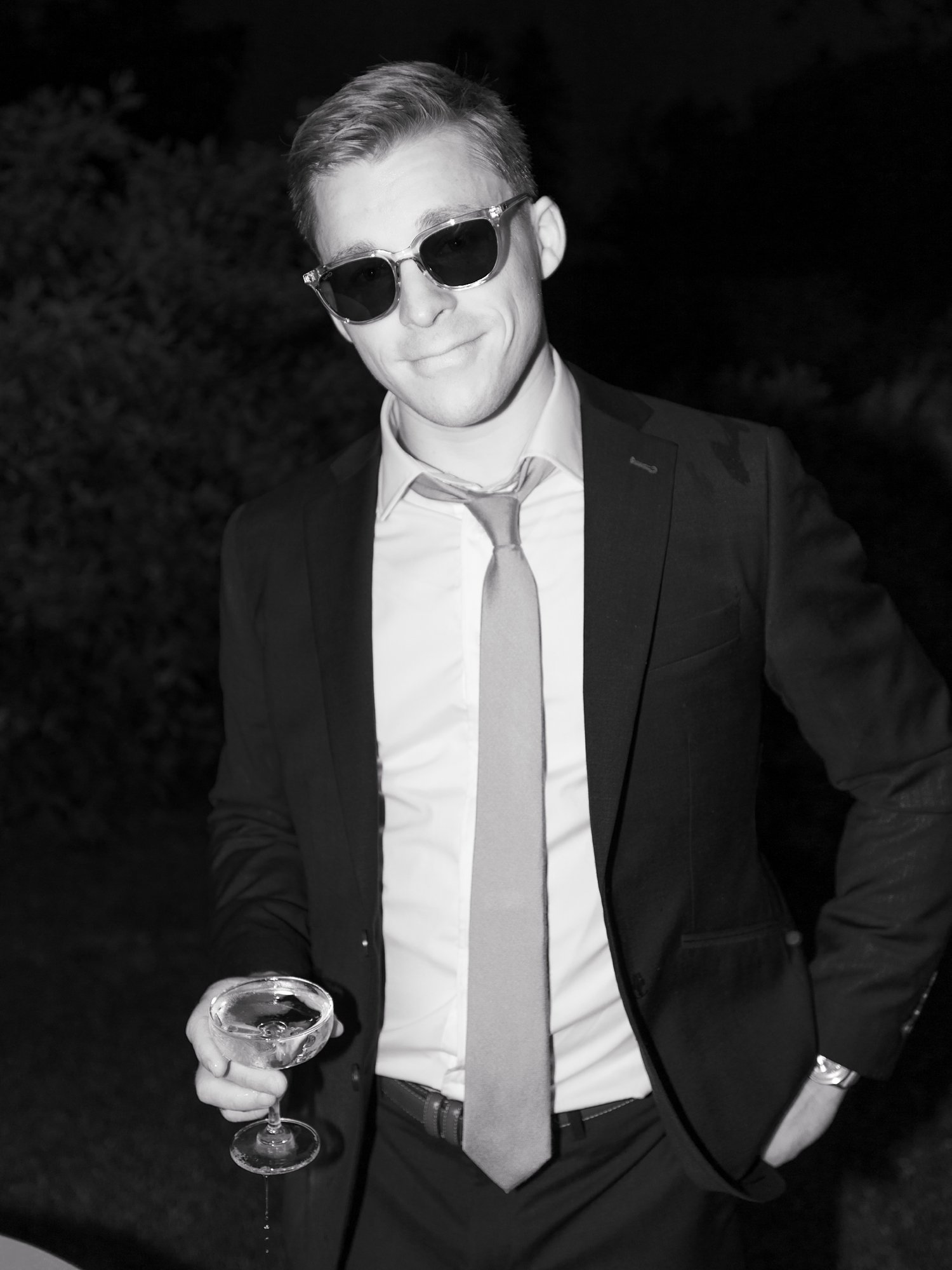 groom smiles holding glass of champagne 