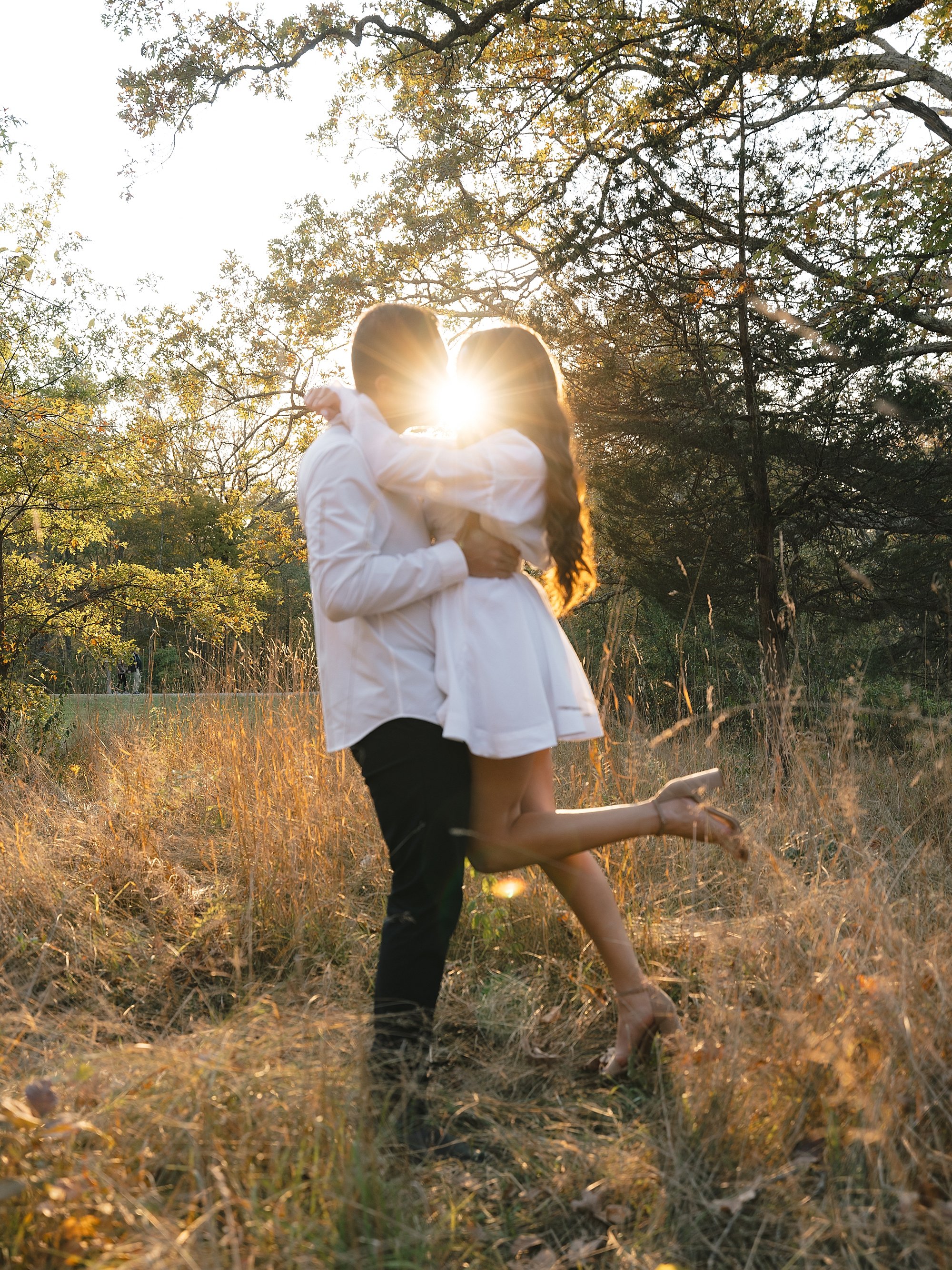 man and woman kiss with sun flare between them at Testimonial Gateway Park