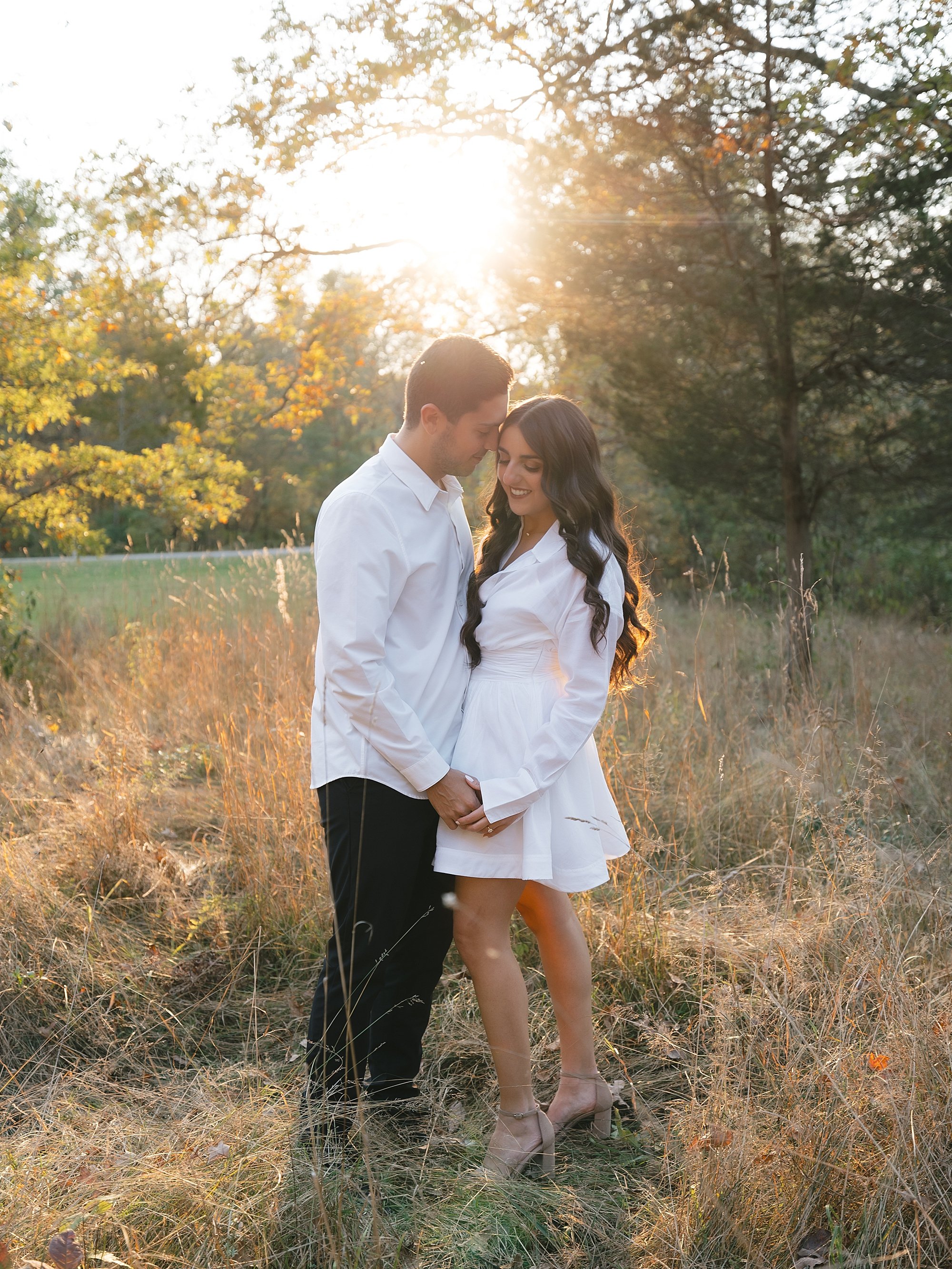 couple stands with sunset behind them during fall engagement photos