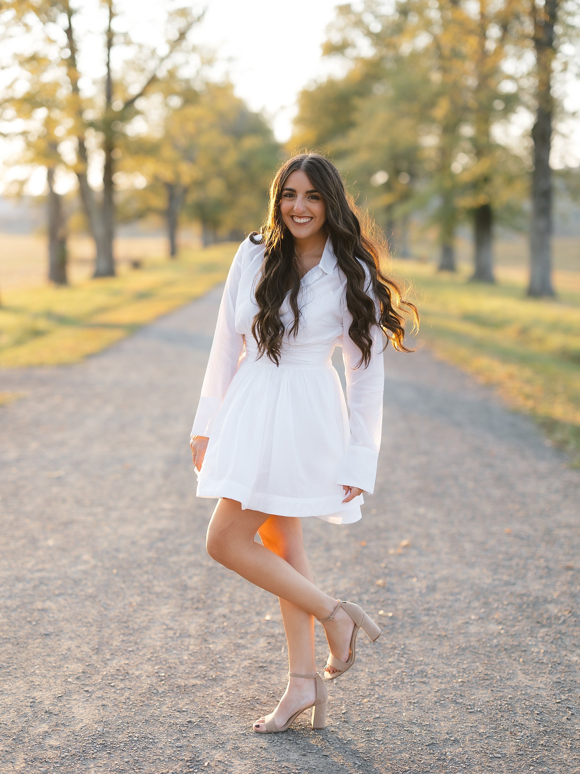 woman stands in pathway at Testimonial Gateway Park in white dress