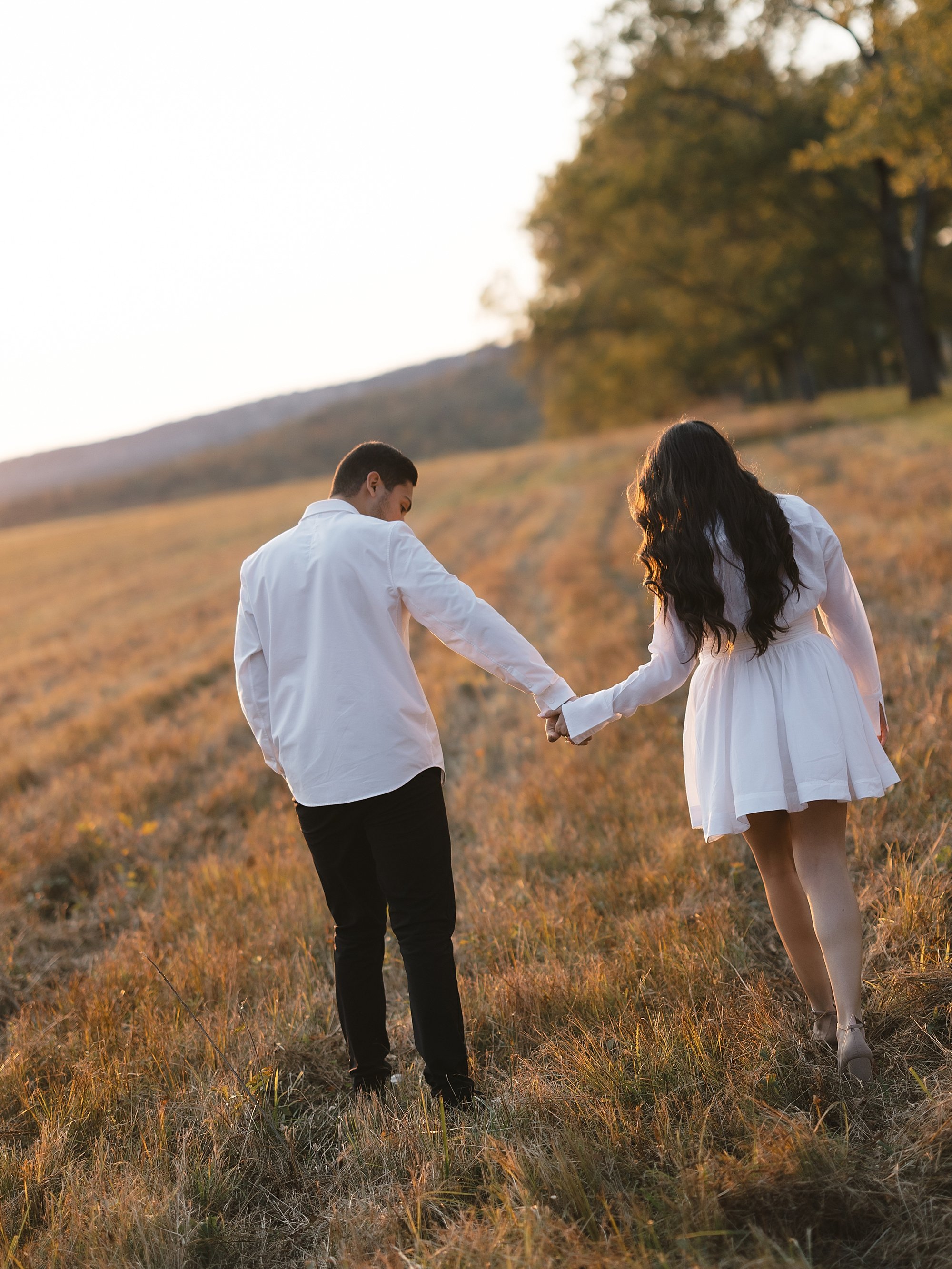 couple holds hands running through field at Testimonial Gateway Park