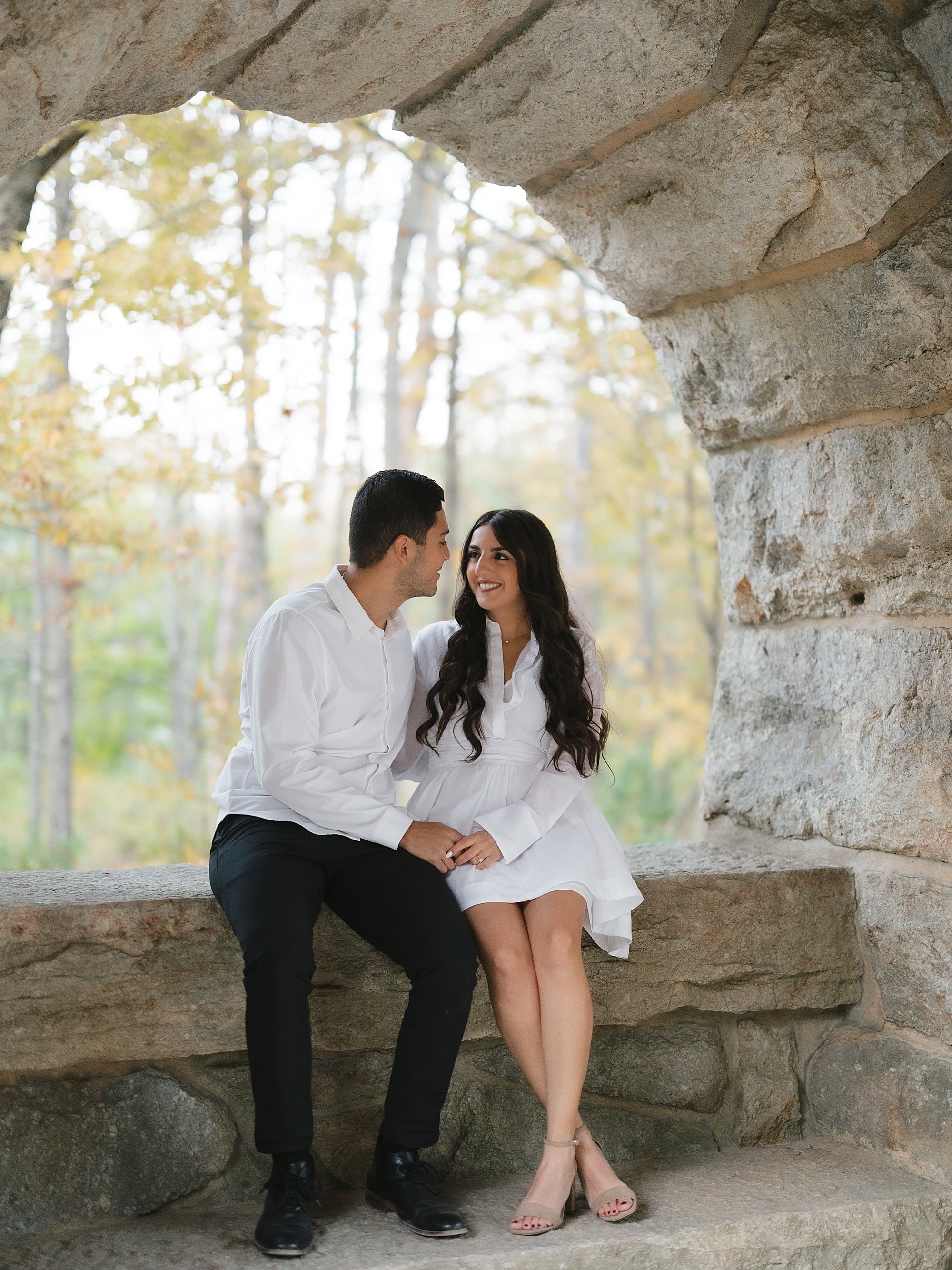 engaged couple sits in stone archway at Testimonial Gateway Park