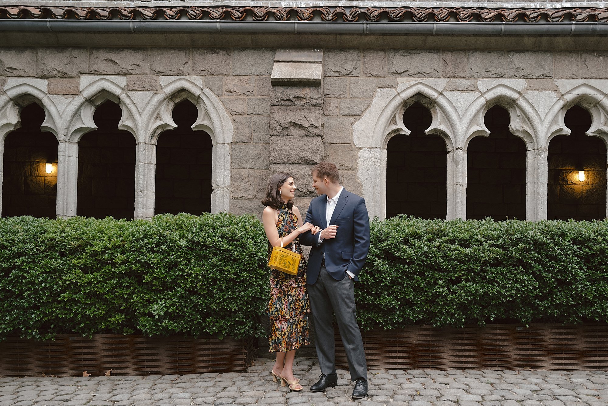 engaged couple stands together outside building at the Met Cloisters