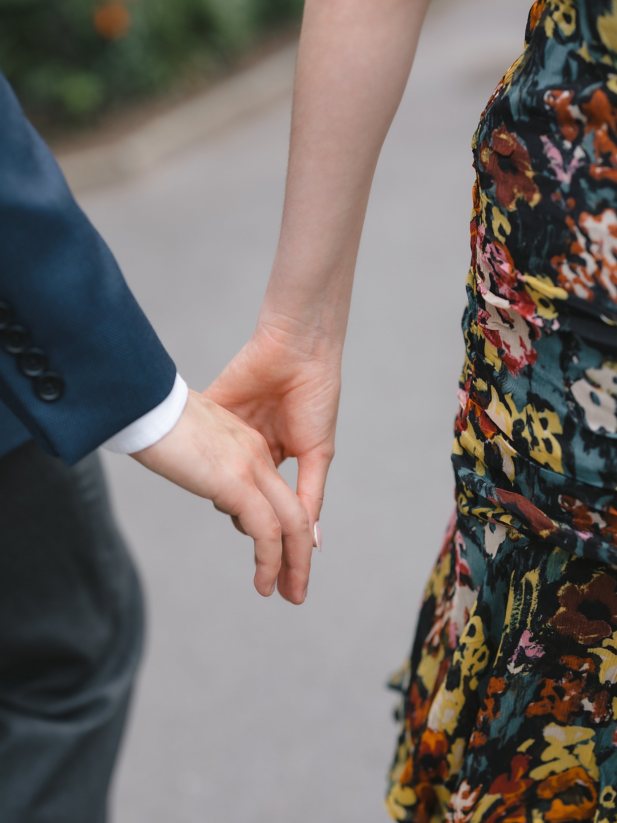 engaged couple holds hands walking through Fort Tryon Park