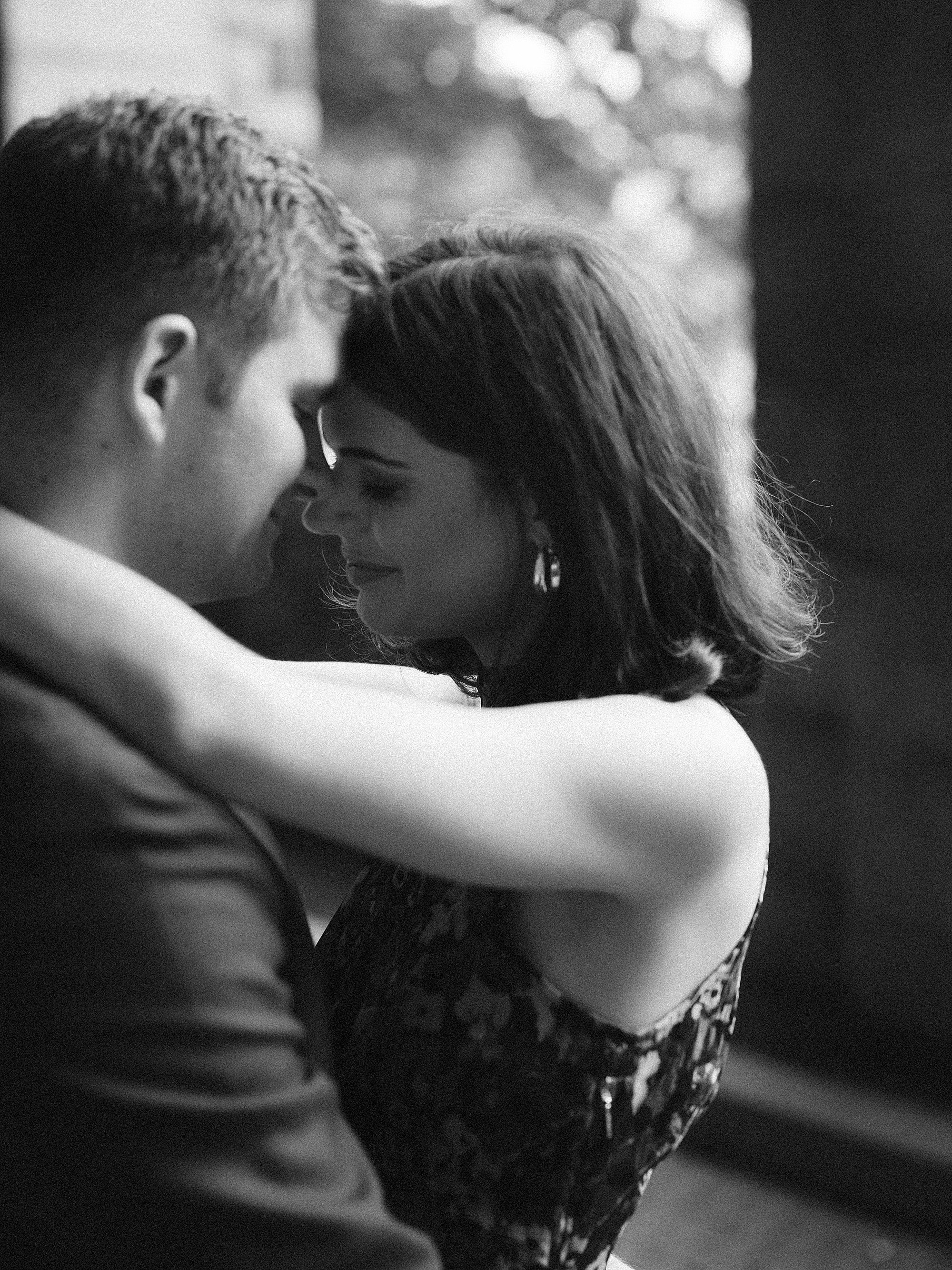 man and woman lean to kiss during engagement portraits at Billings Arcade in Fort Tryon Park