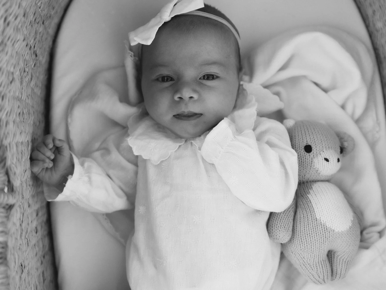 black and white photo of baby laying in Moses Basket