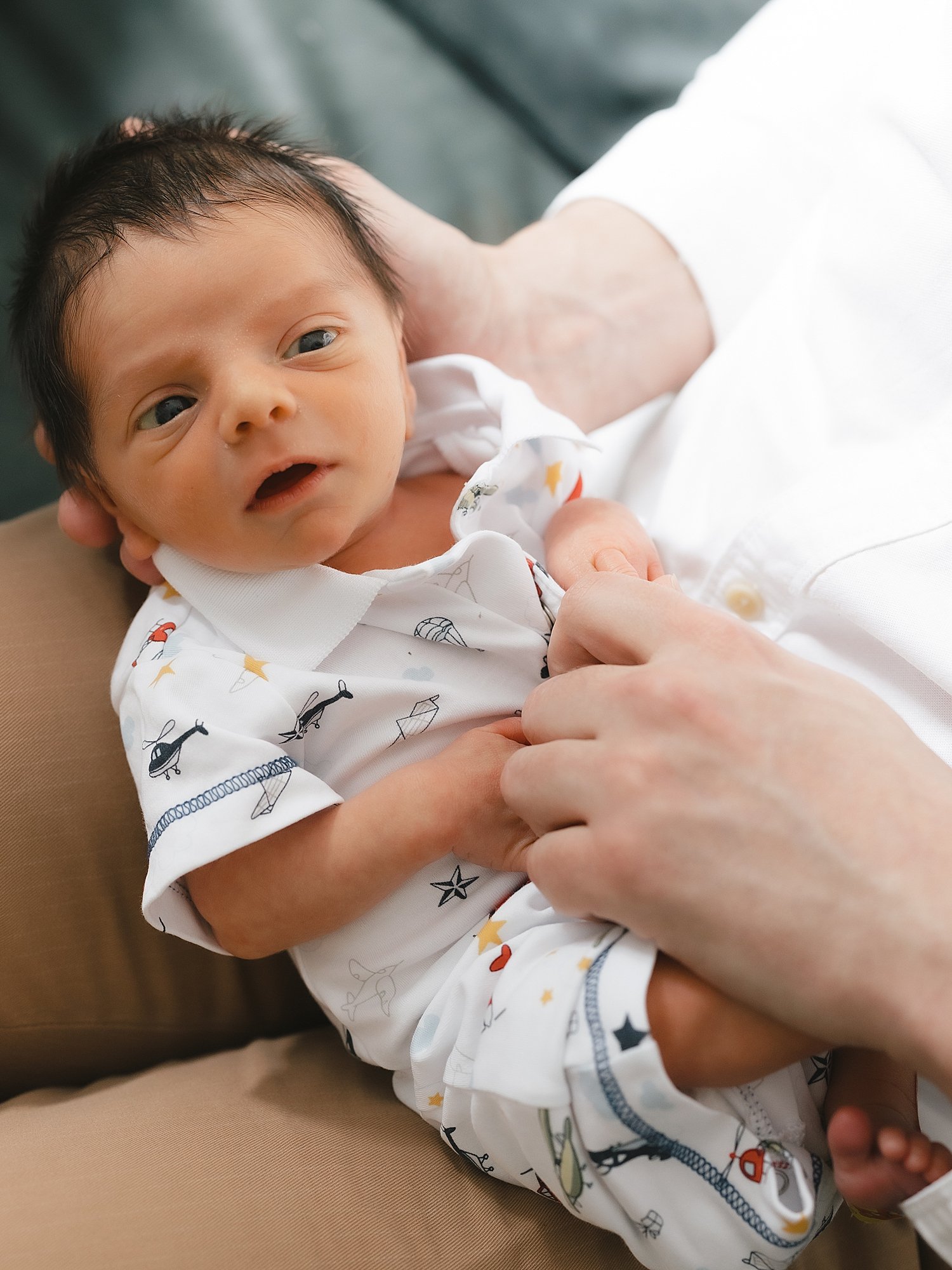 dad holds newborn son on lap during family session at home in Greenwich CT