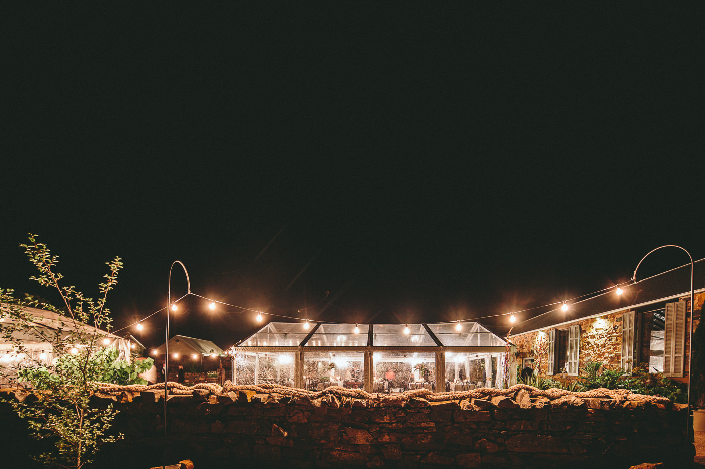  Clear Marquee at night lit by chandeliers and festoon lighting 