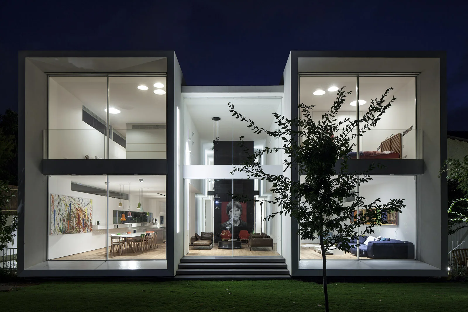 FLOATING TUBES HOUSE The project stands by a huge beautiful ficus boulevard. From the start it was obvious to us that we want it to be a main theme in our design. In order to insert the outdoor to the indoor we designed the long tubes. Transparent edges, sealed on the sides. On one end the garden, and on the other end the ficus. Besides the house, beyond the sealed sides, the neighbors. Almost invisible while in the house. From every point inside the tube, nature reveals. village within the city. But symmetry and order are not sacred. They are the frame of operation. They are not the content. As we enter the project things get dirty. The staircase is coated with black tin that was soaked in kuprum salt. Wild and industrial. The wooden floor is not tacky, it is a bit broken and very scratched. The joyful colorful chandelier, and part of the furniture were bought in a caribbean market. The tubes are only the platform which carries real life emerging inside. Site area: 1050 sq | built area: 750 sq Architect in charge: Hadas Wexler | Project management: Ofir Kleiman | Photographs: Amit Geron
