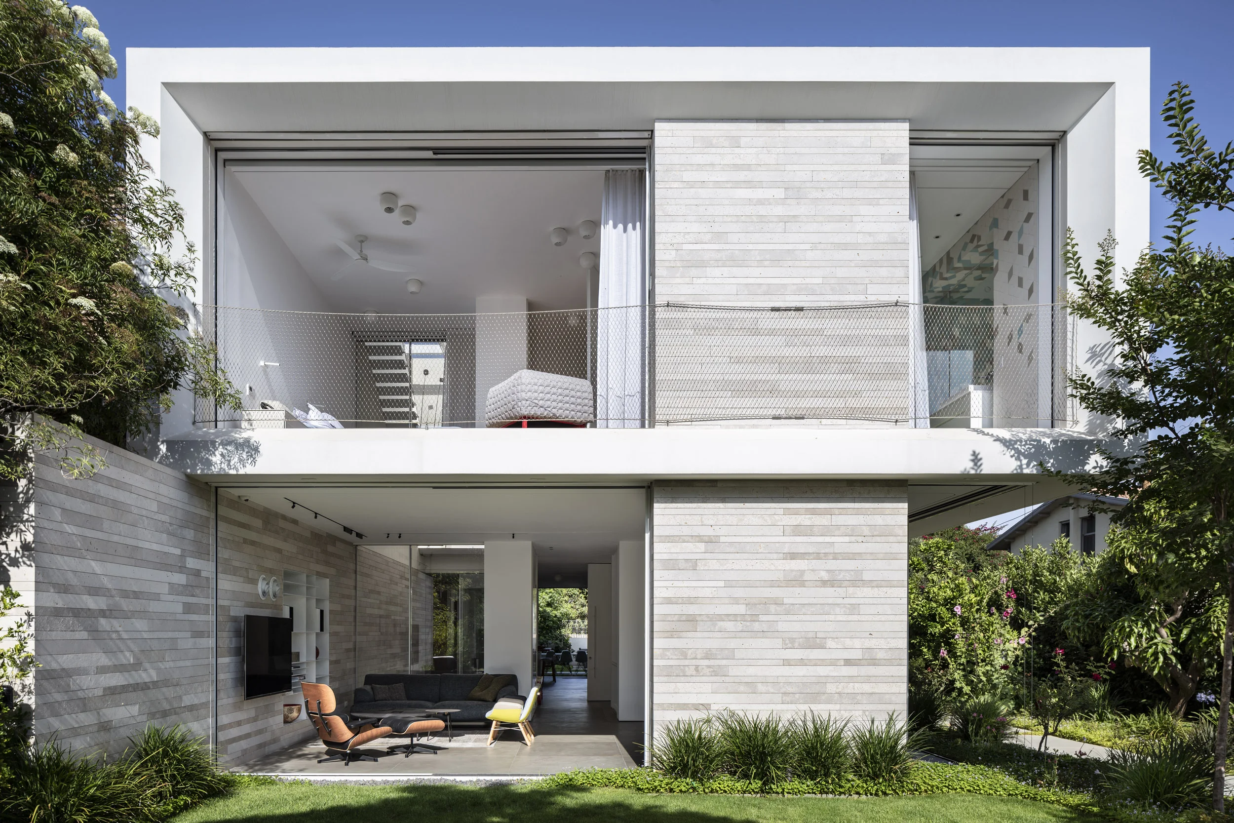 FLOW A fluent yet great gesture of linking indoor and outdoor was our main guide in this project. The house is built on a dual plot, and our challenge was giving the costumers a sense of privacy, intimacy and freedom with in their home. The project is surrounded by natural light and vegetation, that flows inside in various methods and locations. The main yard, overlooking the living room feels like a natural extension of the built area. Blurring the boundaries of indoor-outdoor. The central patio strokes with natural light and nature even the most intimate parts of the house, preserving a constant dialogue between in and out at every position one may stand. The upper level floats above the ground floor, leaning over the massive stone wall, allowing the flow of movement and air throughout the house. The east-west orientation of the house is present in every glimpse and frames the open views and perfect air flow. Site area: 650 sq | Built area : 500 sq Architect in charge: Naama Hayun | Project Management : Shahar & Roi
