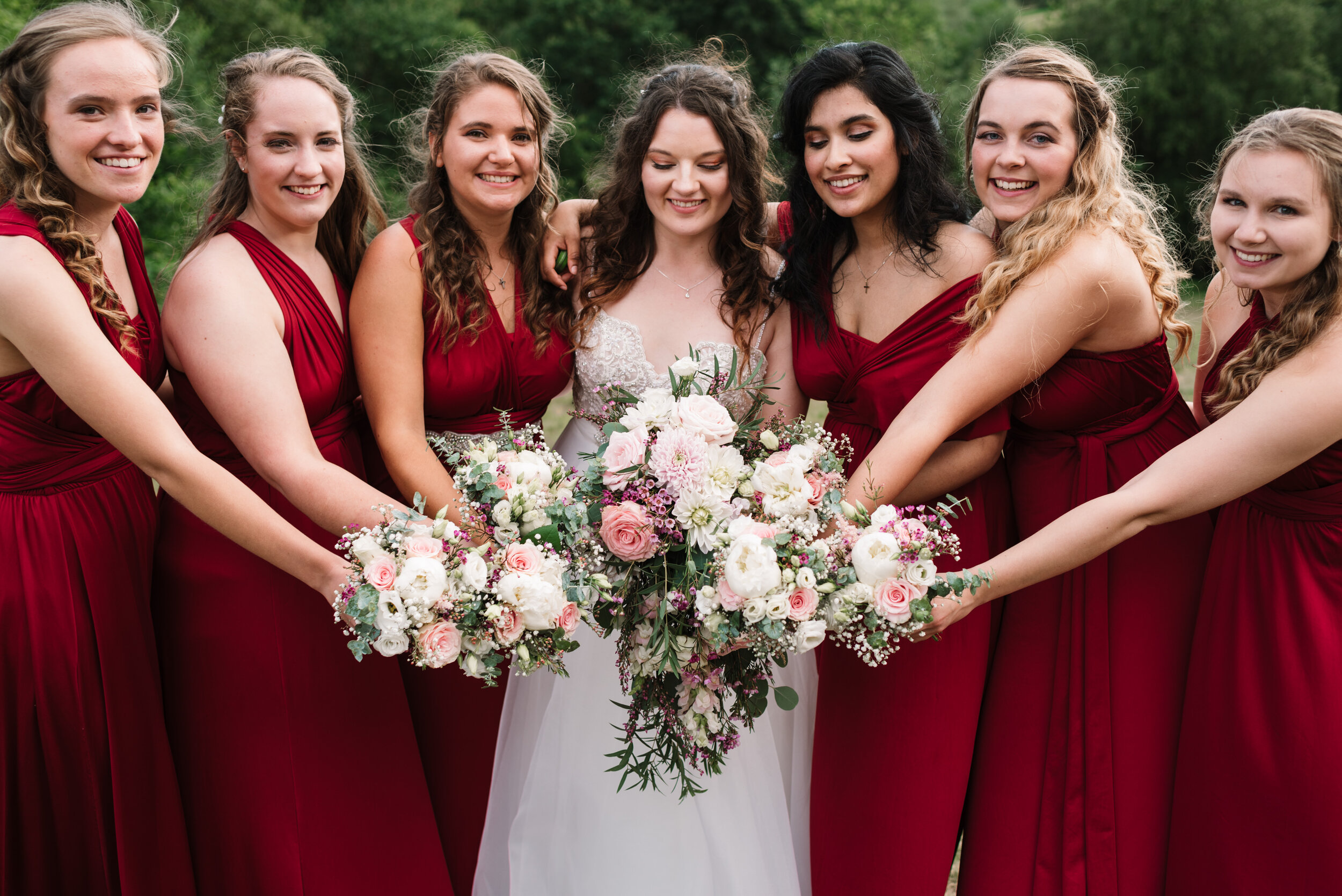 Bride and bridesmaids wearing red dresses on wedding day with bouquets