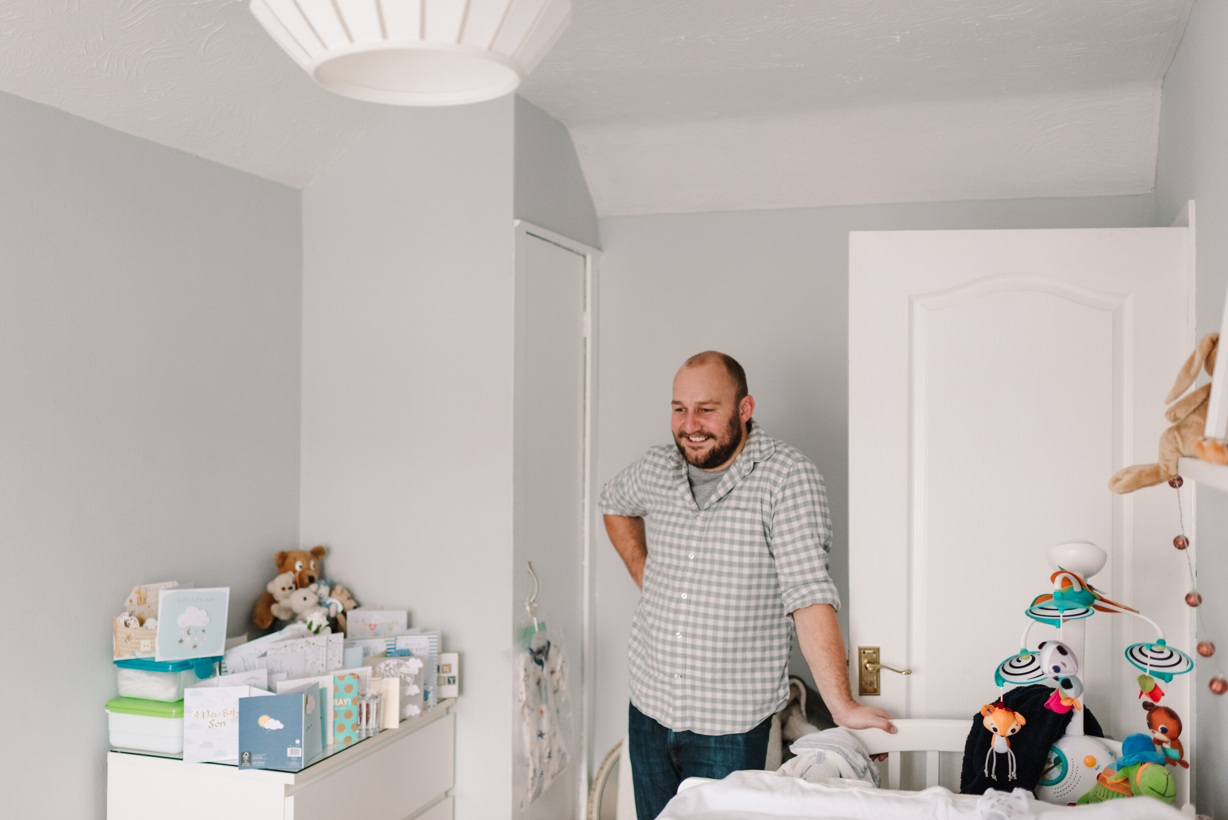Dad looking proudly at baby son in bedroom