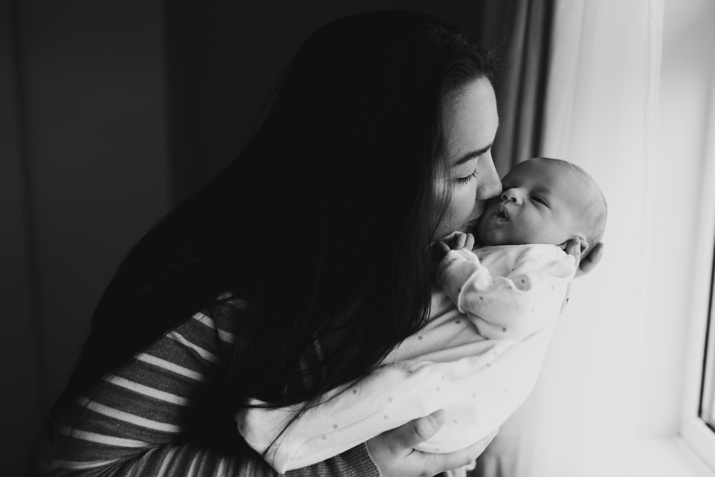Mother kissing baby's face in black and white photo
